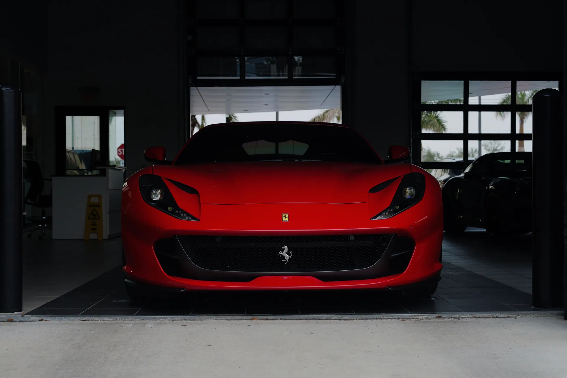 A striking red sports car parked in a contemporary garage setting, showcasing luxury design.