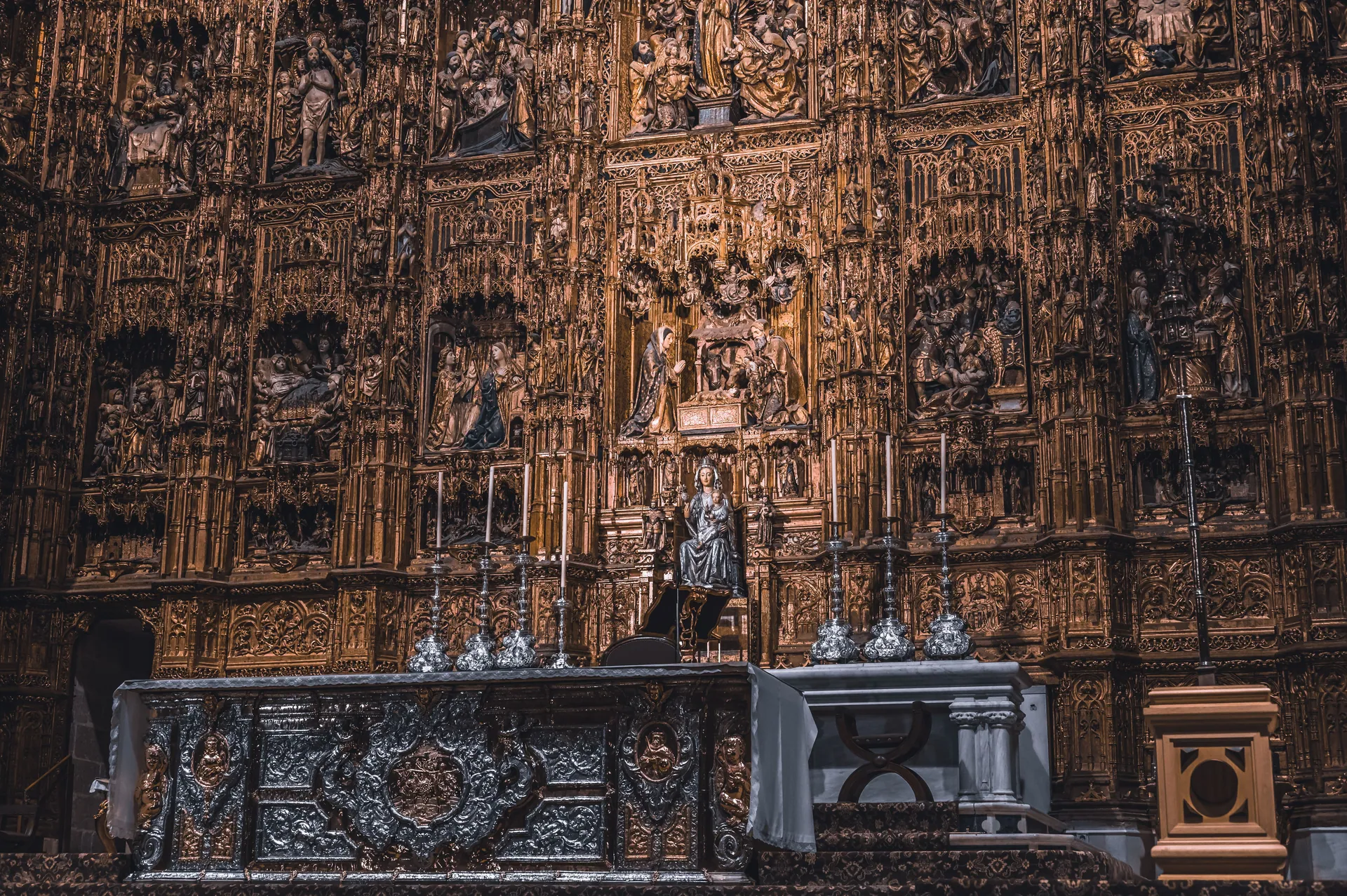 Golden altar with ornate religious art in Seville Cathedral, showcasing detailed craftsmanship.