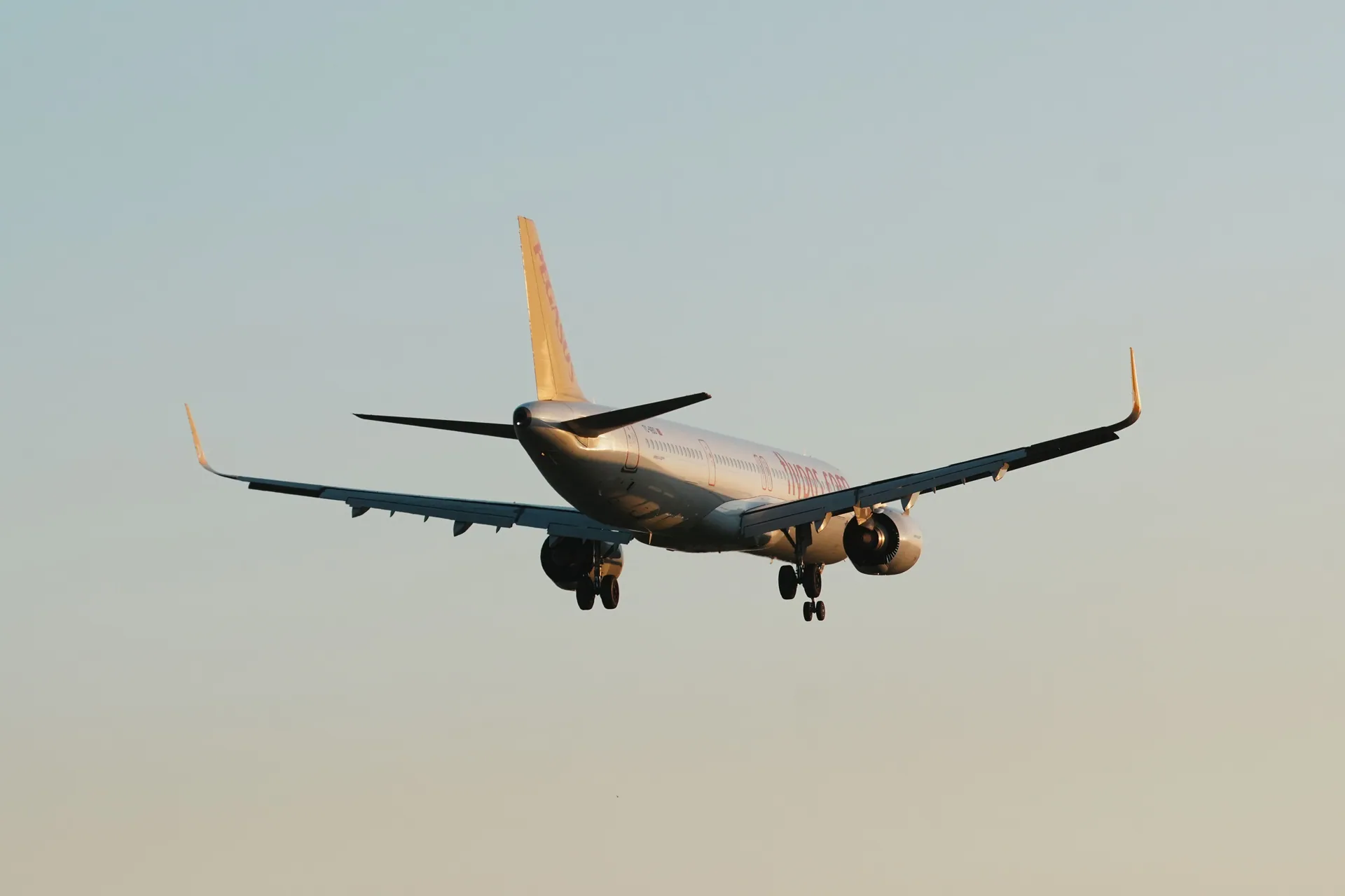A commercial airplane descends smoothly over Istanbul during daytime.