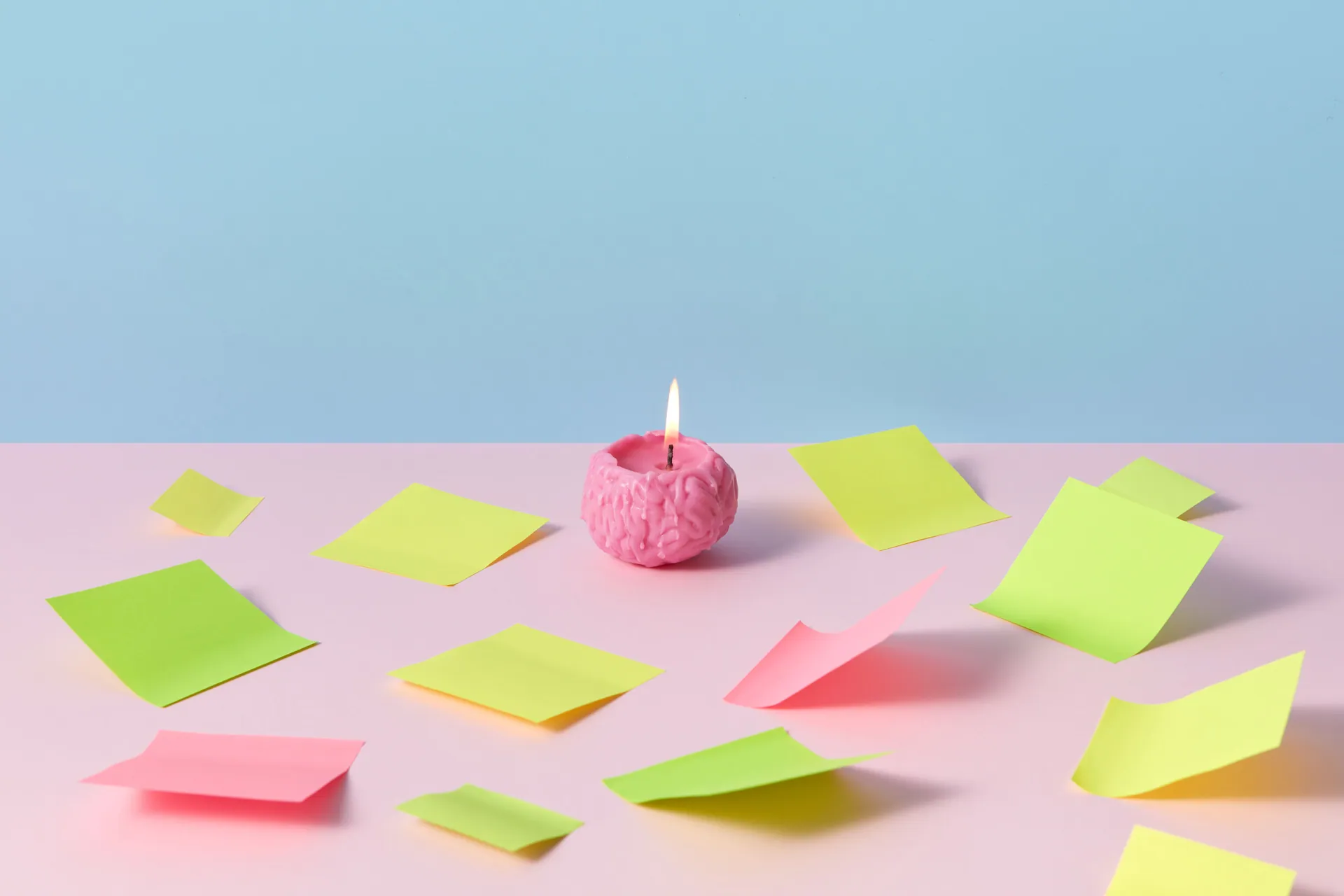 A pink brain candle lit among colorful sticky notes on pastel background, evoking creativity.