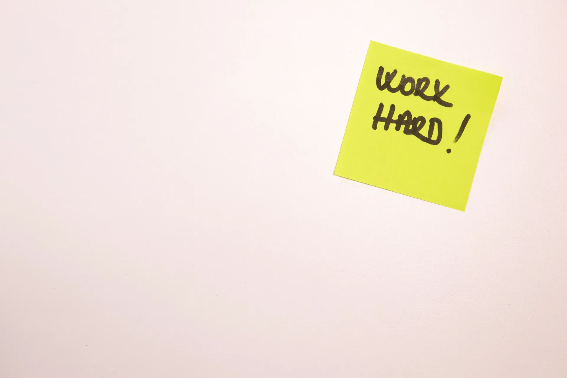 Bright yellow sticky note on white background with 'Work Hard' written, ideal for motivational content.
