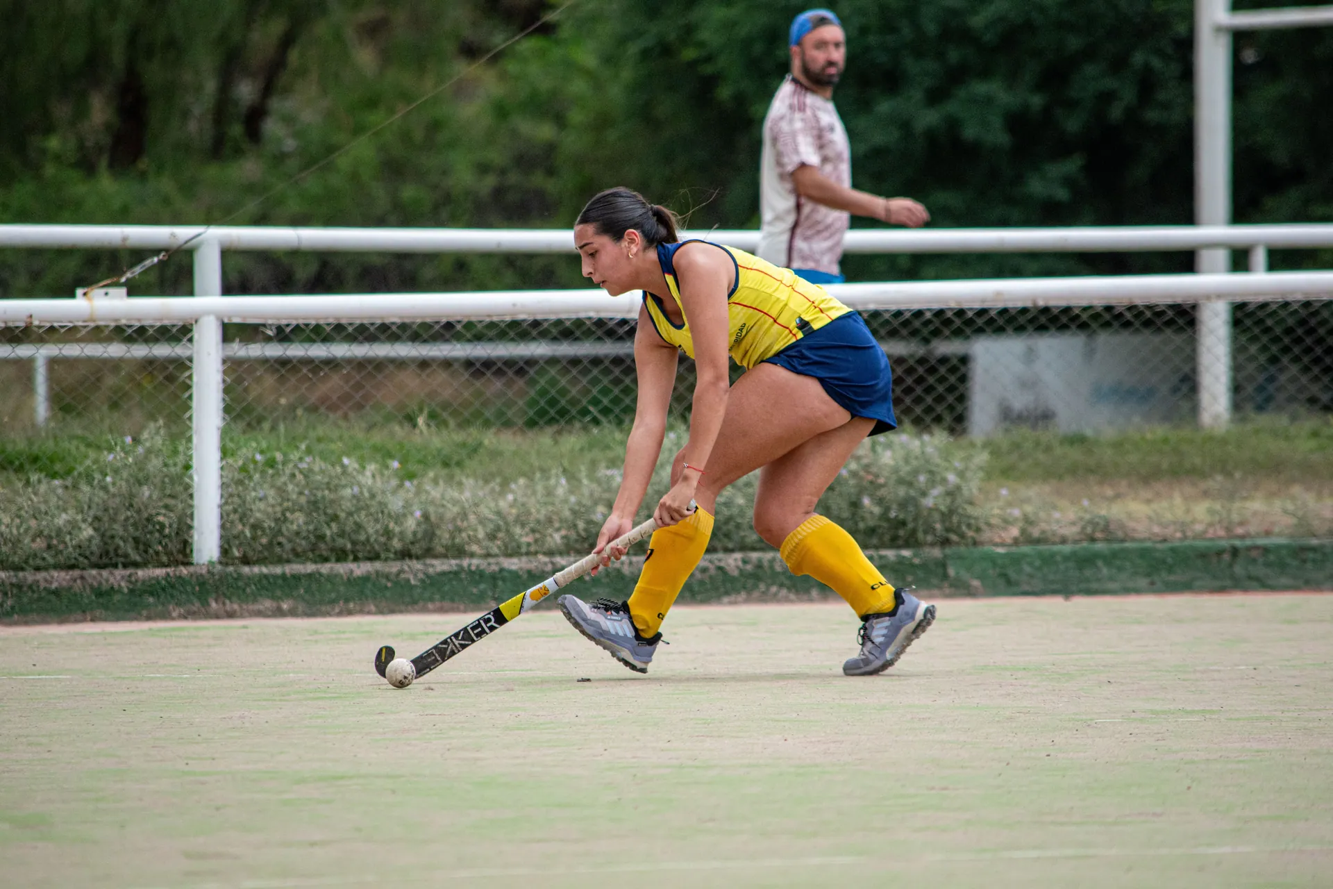 Dynamic field hockey scene with female player hitting the ball during a match.