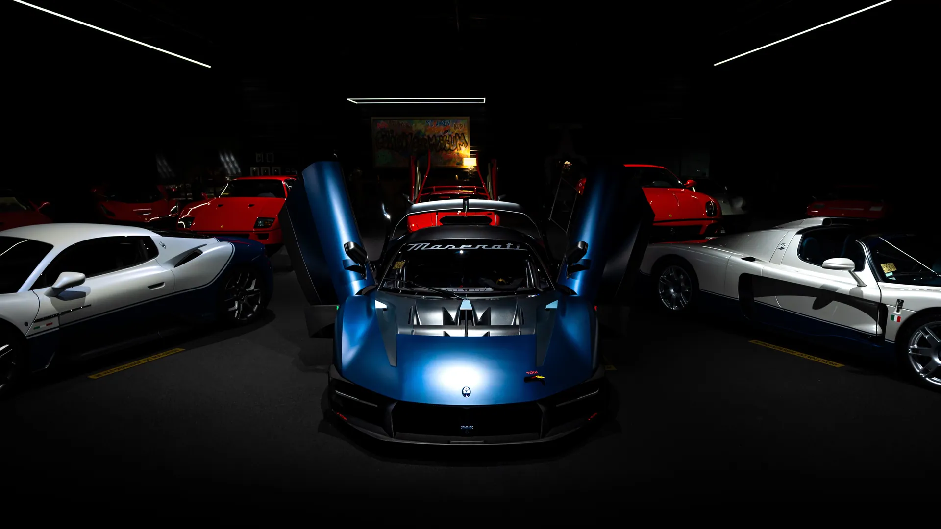 Elegant lineup of Maserati sports cars with doors open in a dark showroom.