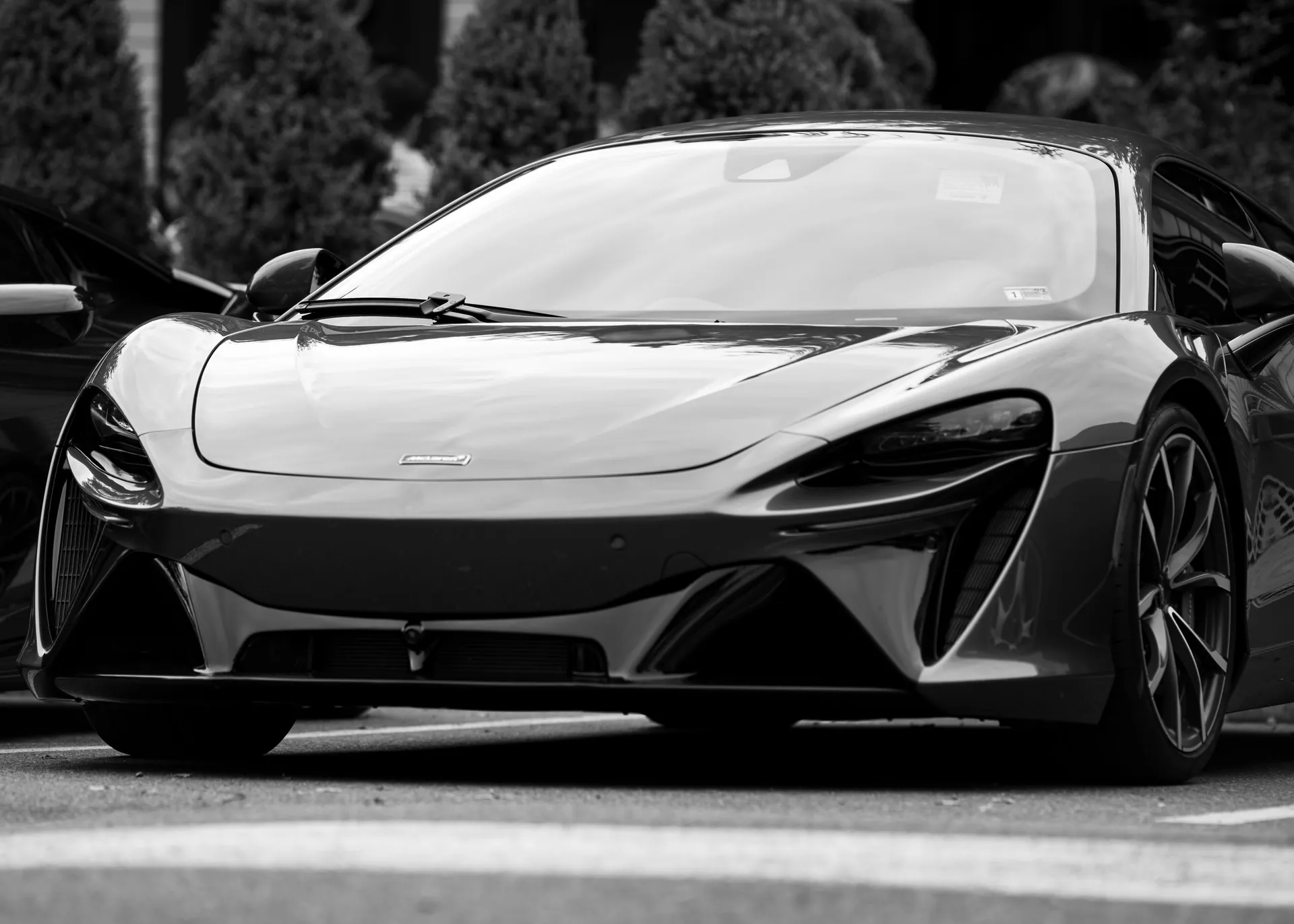 Monochrome image of a sleek luxury sportscar parked outdoors, capturing modern design.