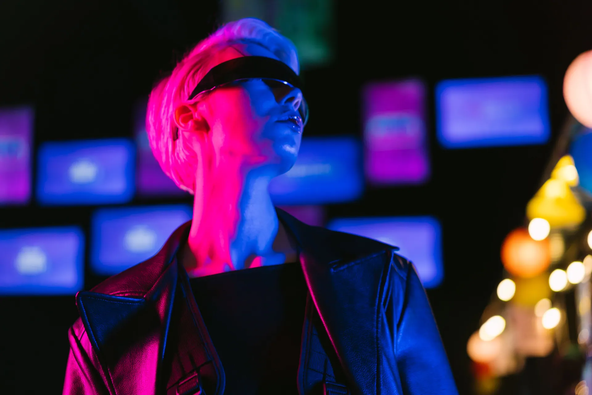 A woman in a leather jacket and sunglasses in a vibrant cyberpunk setting with neon lights.