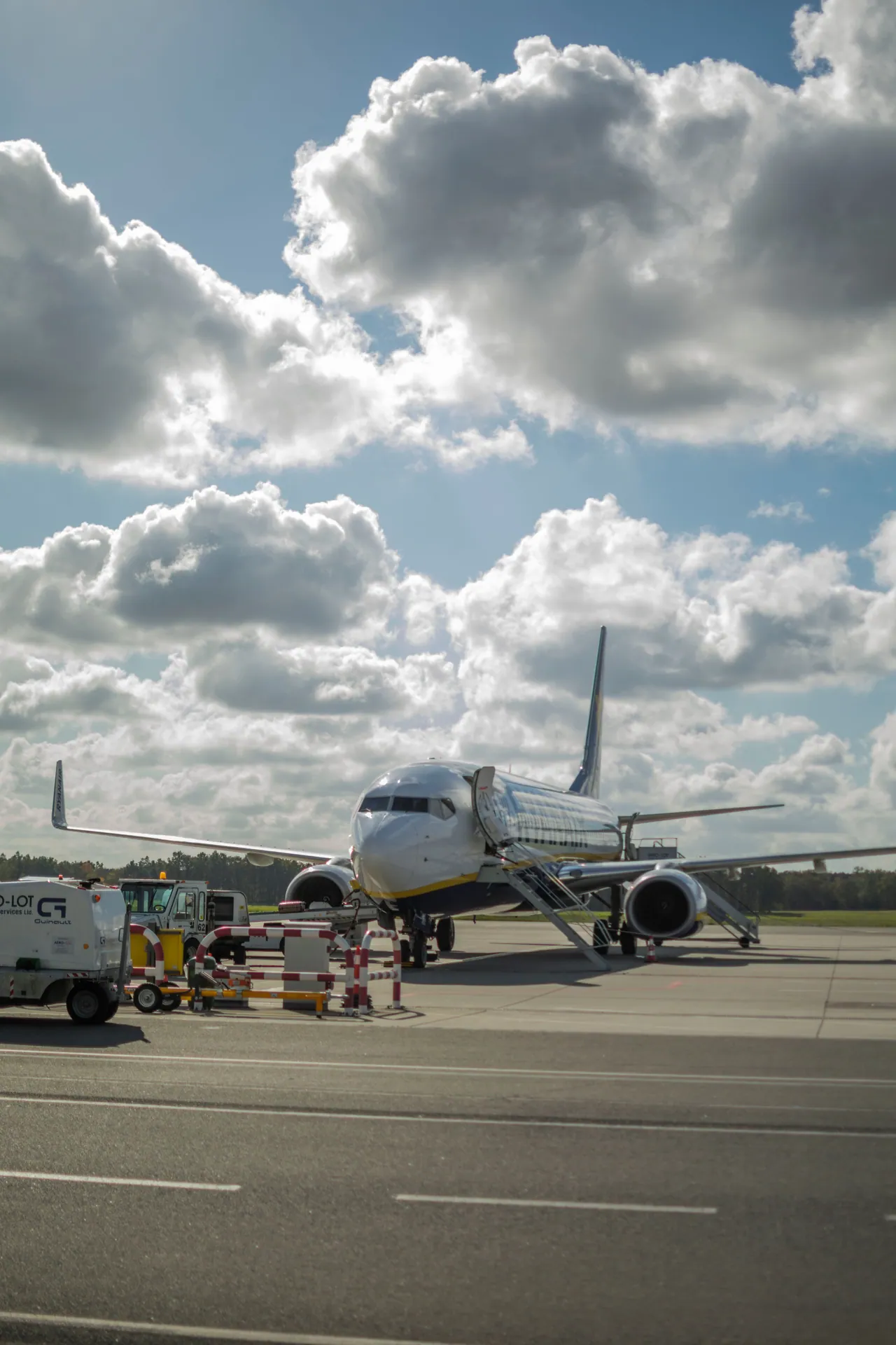 Airplane on the runway at Wrocław Airport beneath a partly cloudy sky.