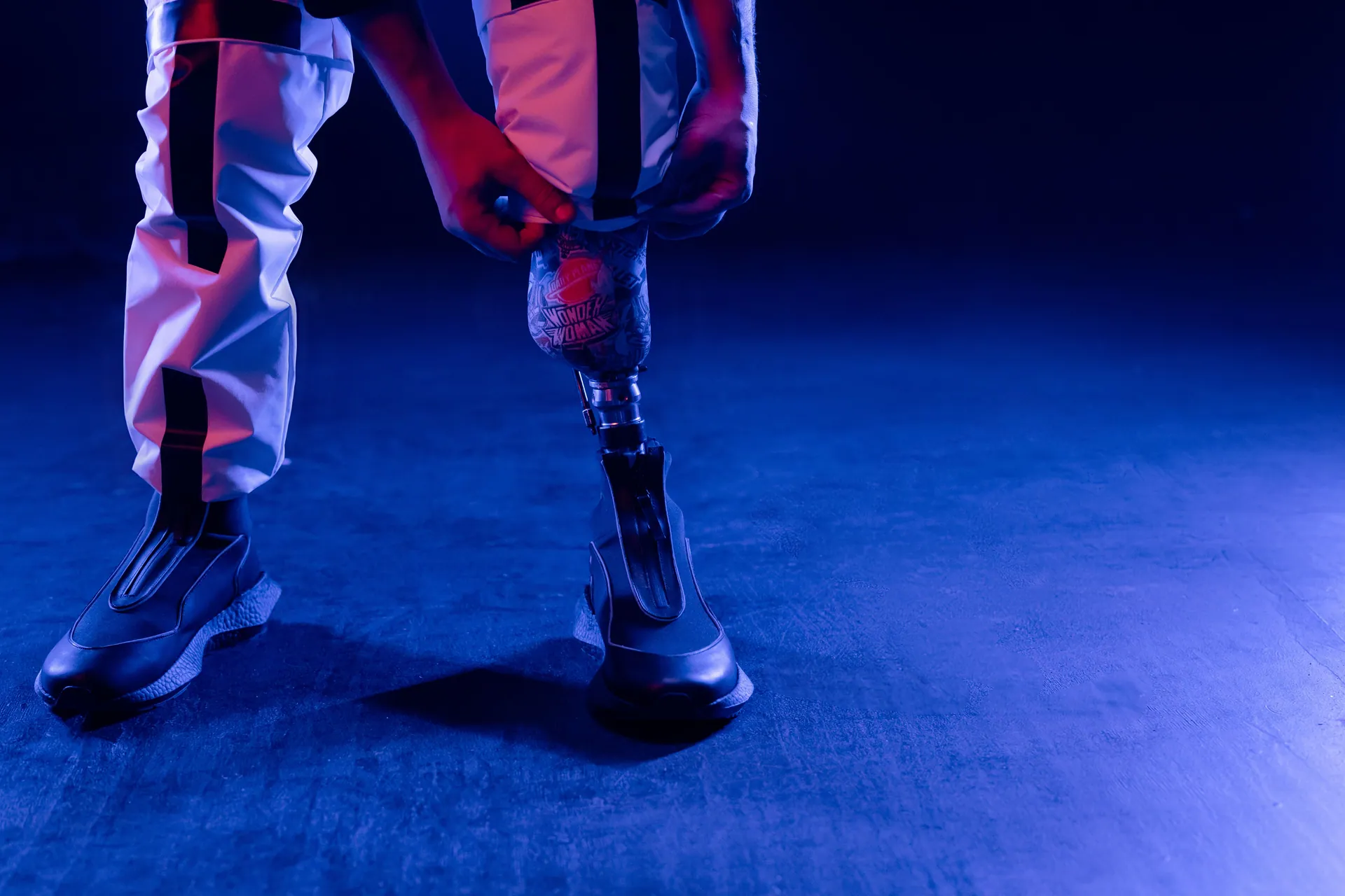 Person adjusting a modern prosthetic leg in a dimly lit setting, showcasing advanced design and technology.