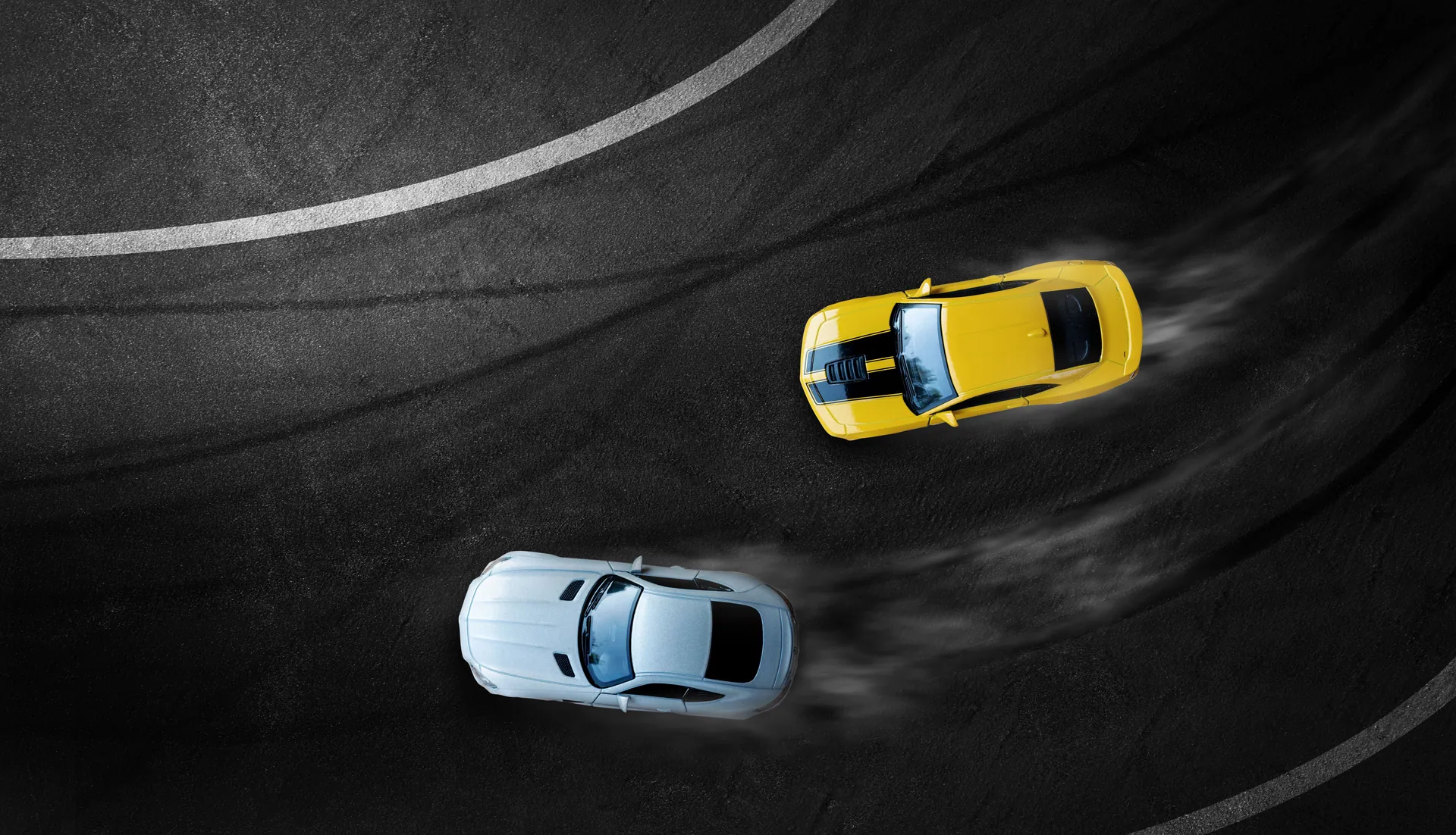 Aerial view of two cars drifting on a curved asphalt track, showcasing precision driving.