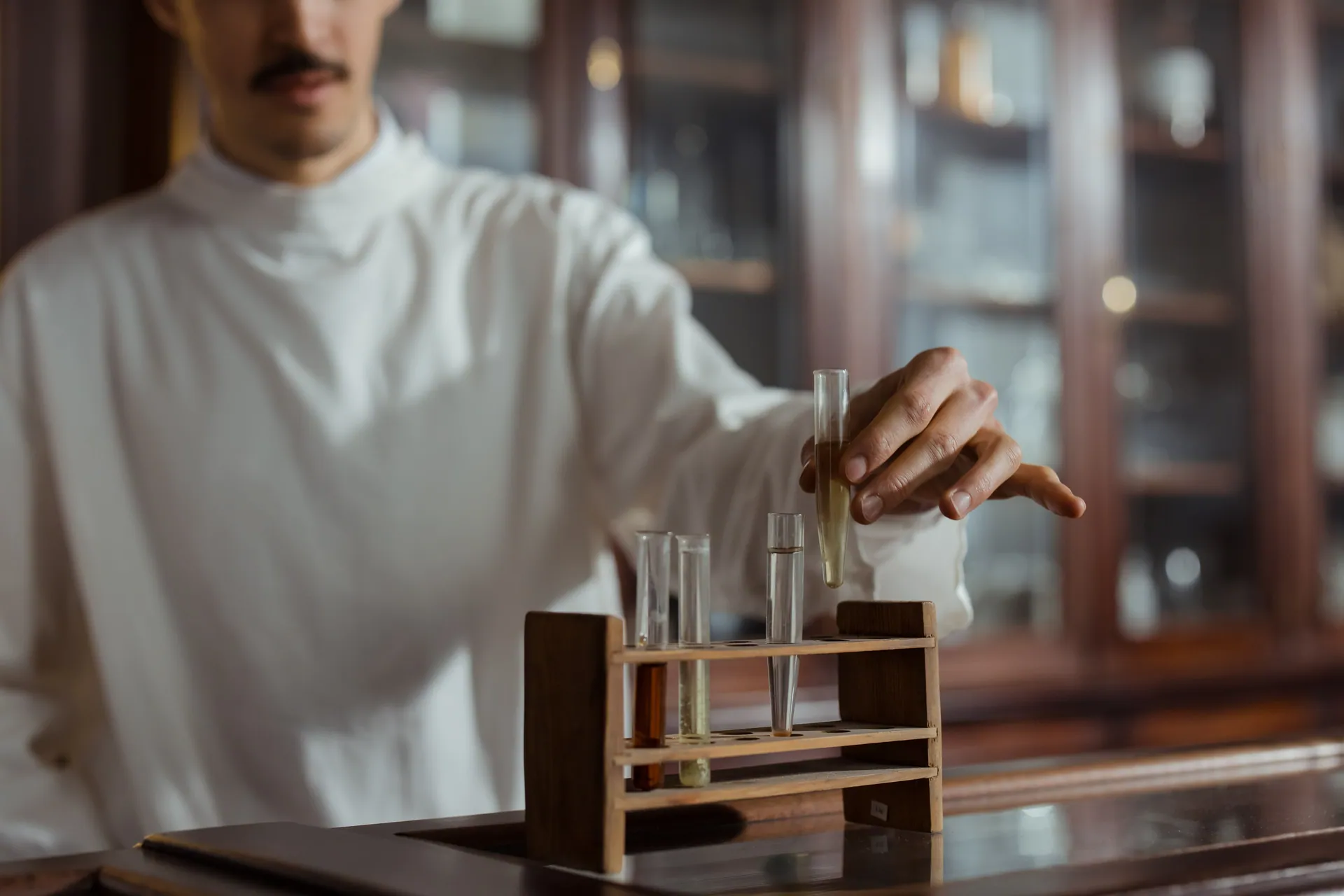 Scientist in lab coat handling test tubes in a laboratory setting.