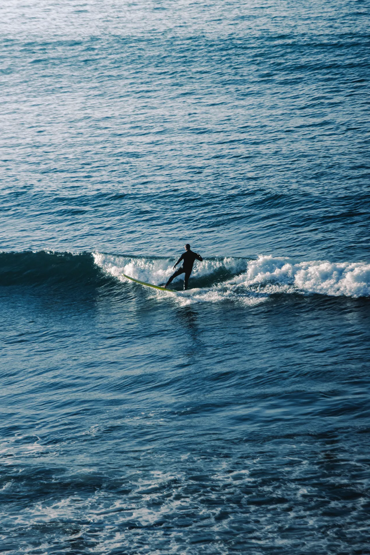 A surfer skillfully maneuvers through the waves of Morocco's turquoise ocean, showcasing the thrill of water sports.