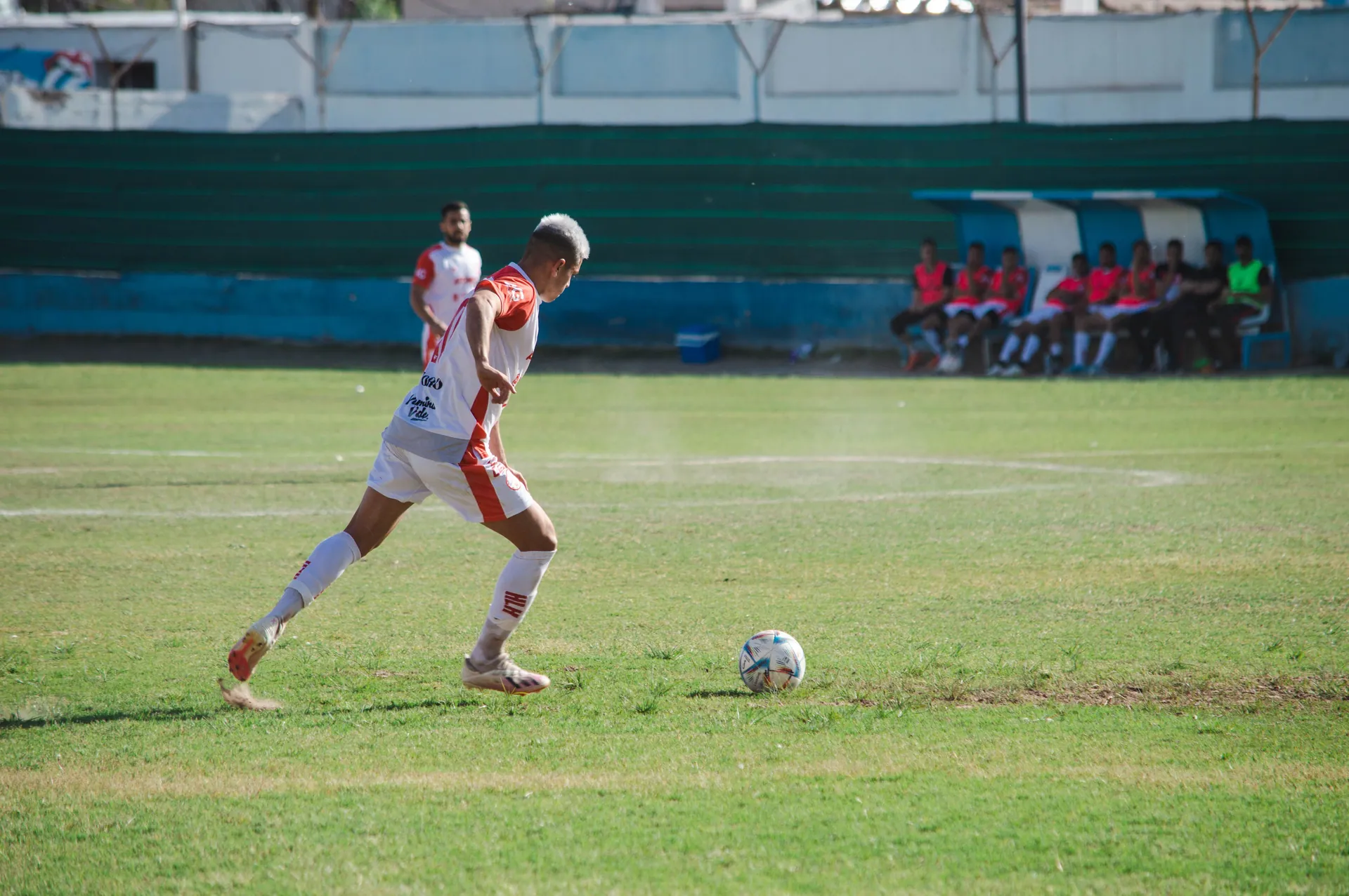 Male soccer player in action on the field during a sunny day match.