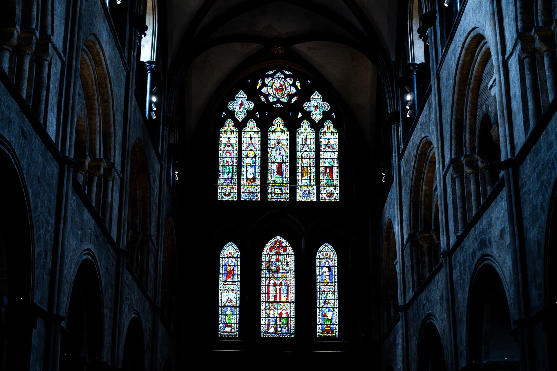 Gothic stained glass windows inside Chichester Cathedral, showcasing intricate religious artistry.