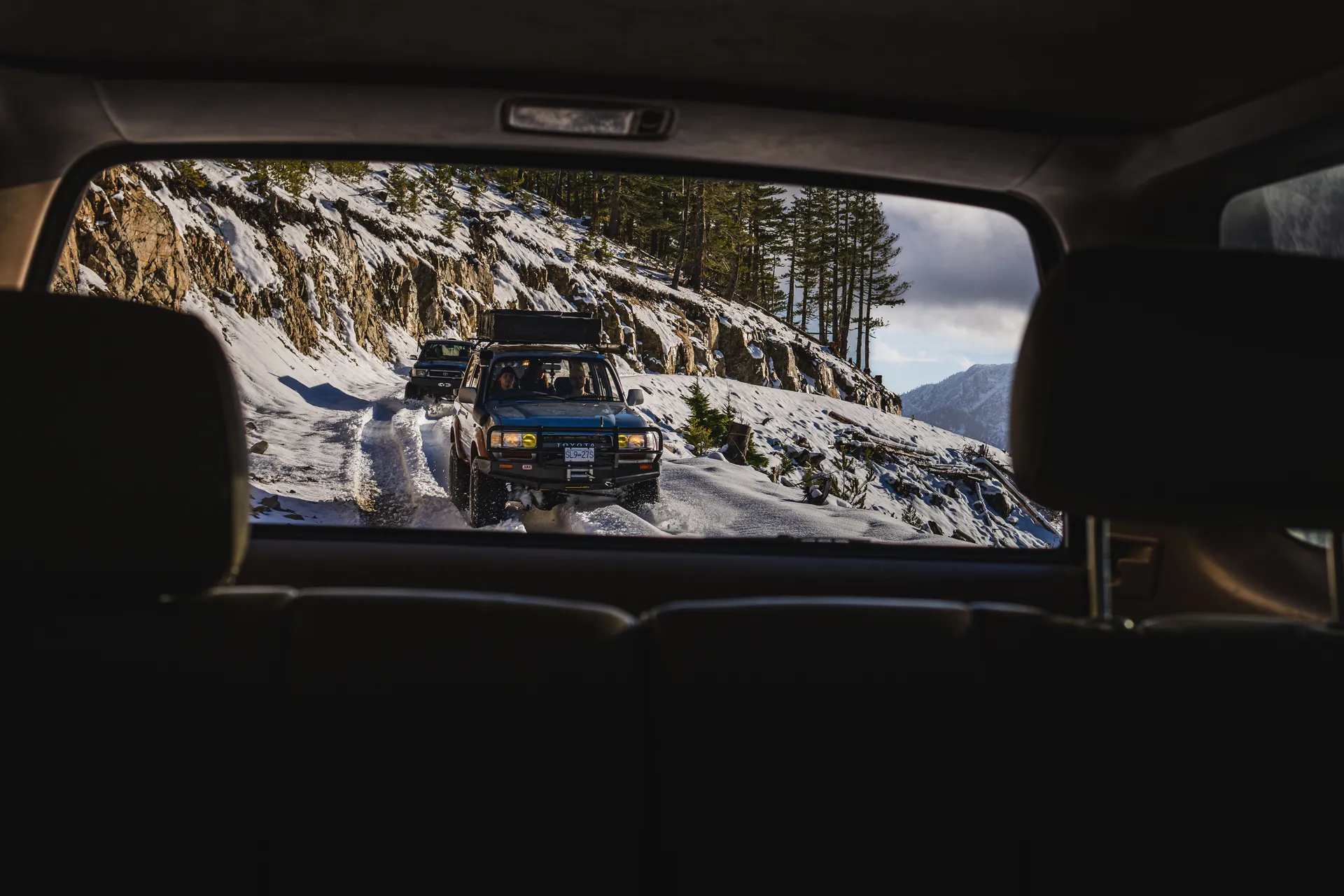 Rugged 4x4 vehicles navigate snowy mountain paths, perfect for adventure travel enthusiasts.