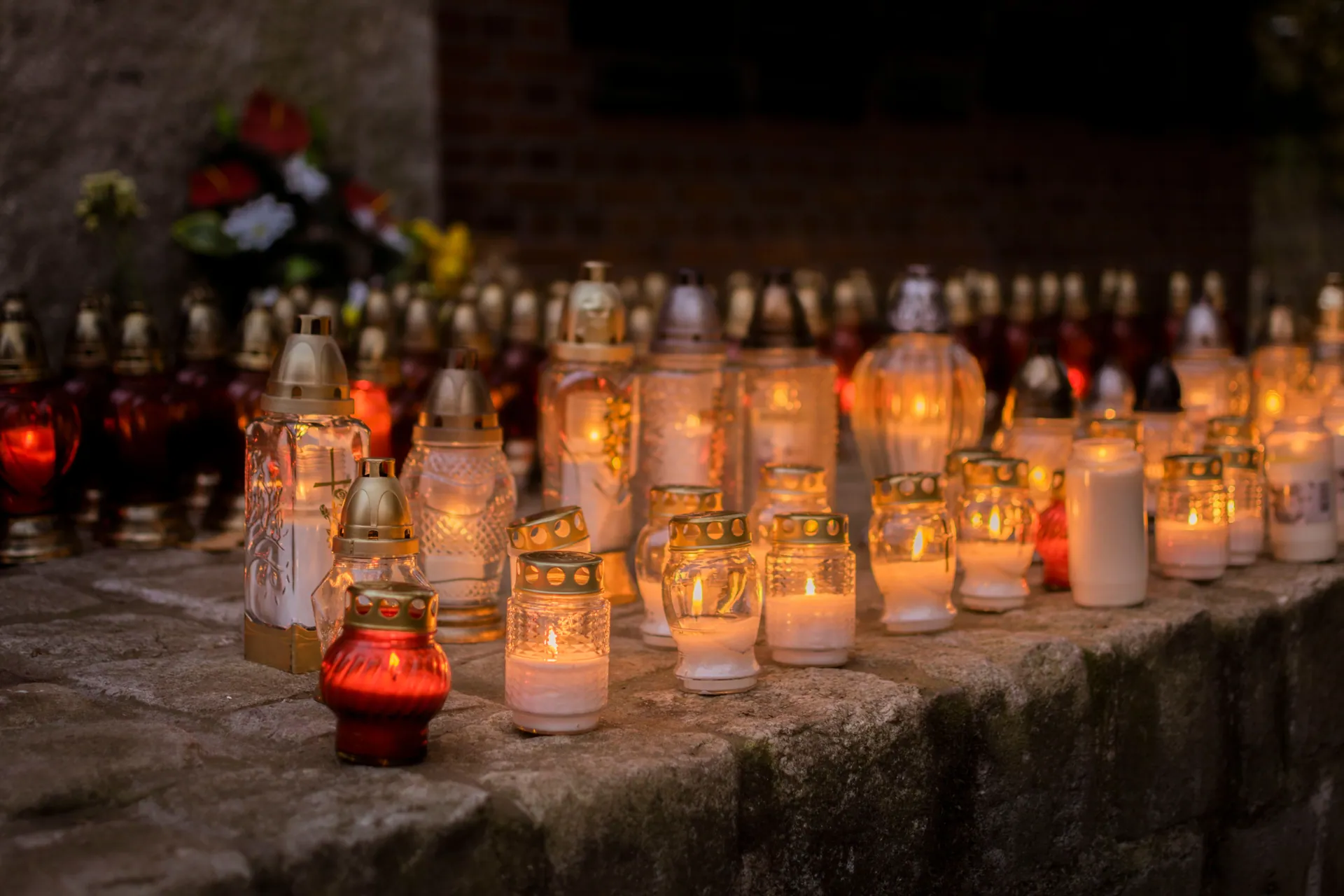 A serene scene of votive candles glowing softly in a cemetery during All Saints' Day.