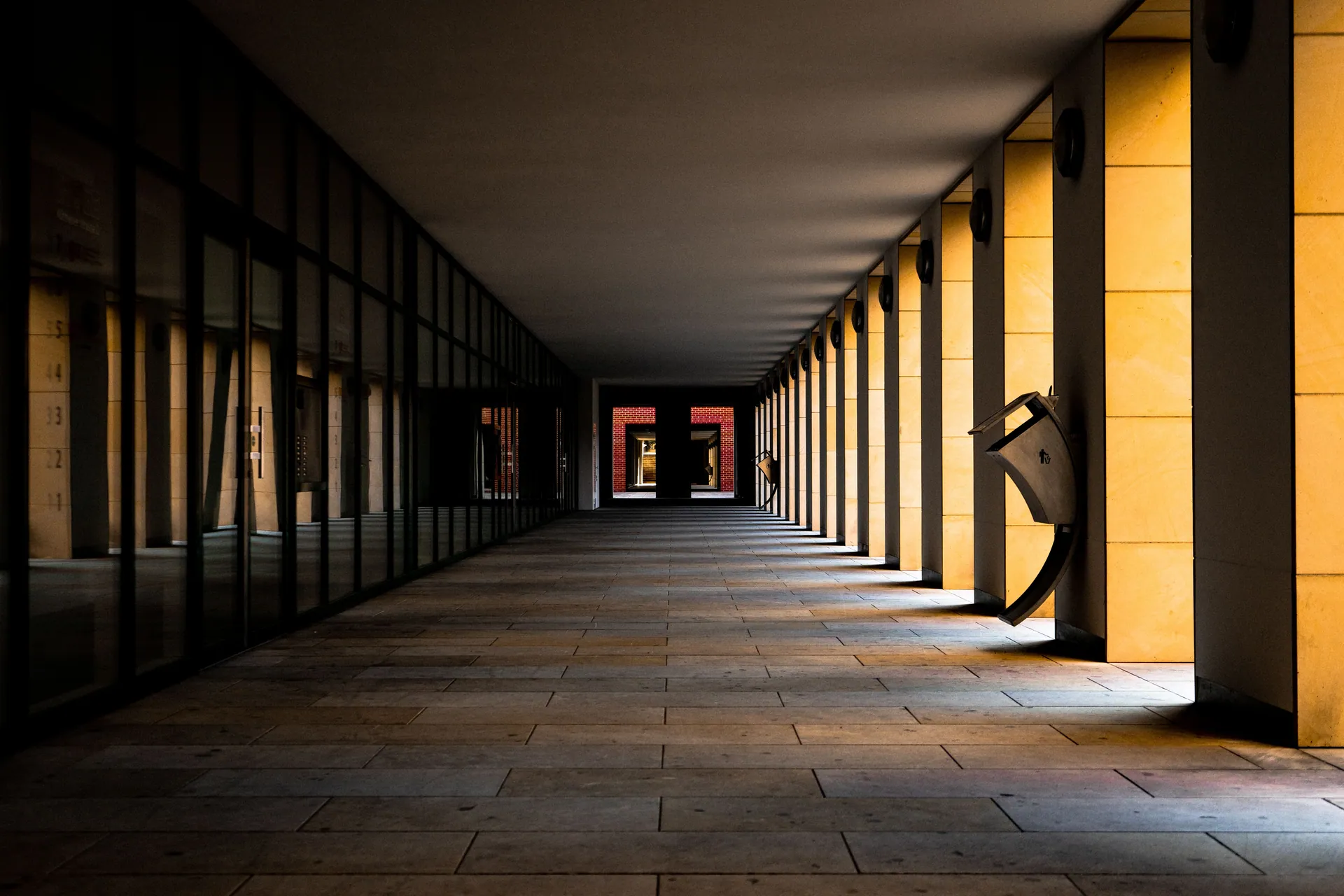 Dramatic view of an empty symmetrical corridor with striking golden columns casting shadows.