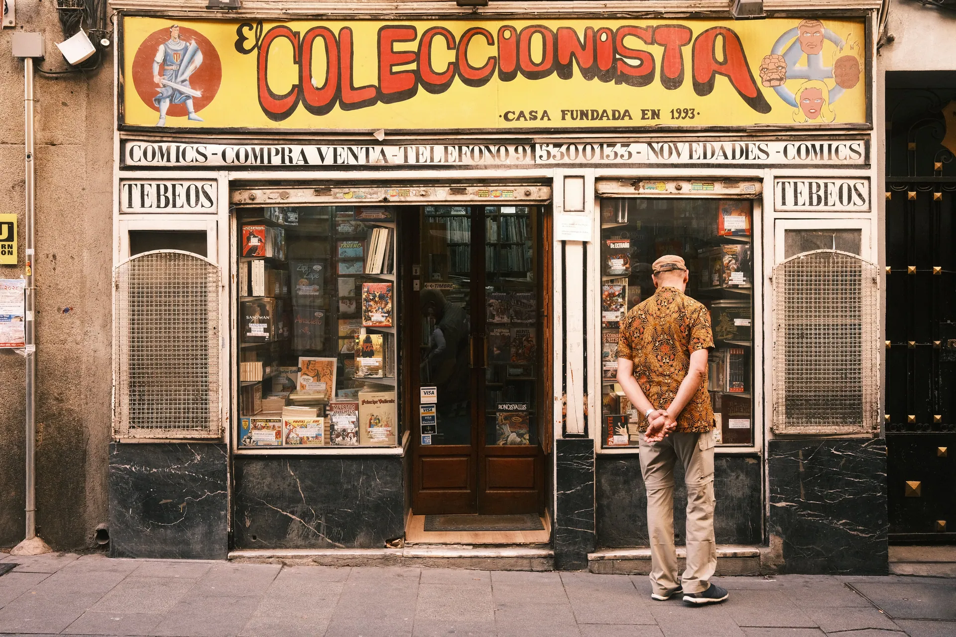 A man window shopping outside a vintage comic store in Madrid, Spain.
