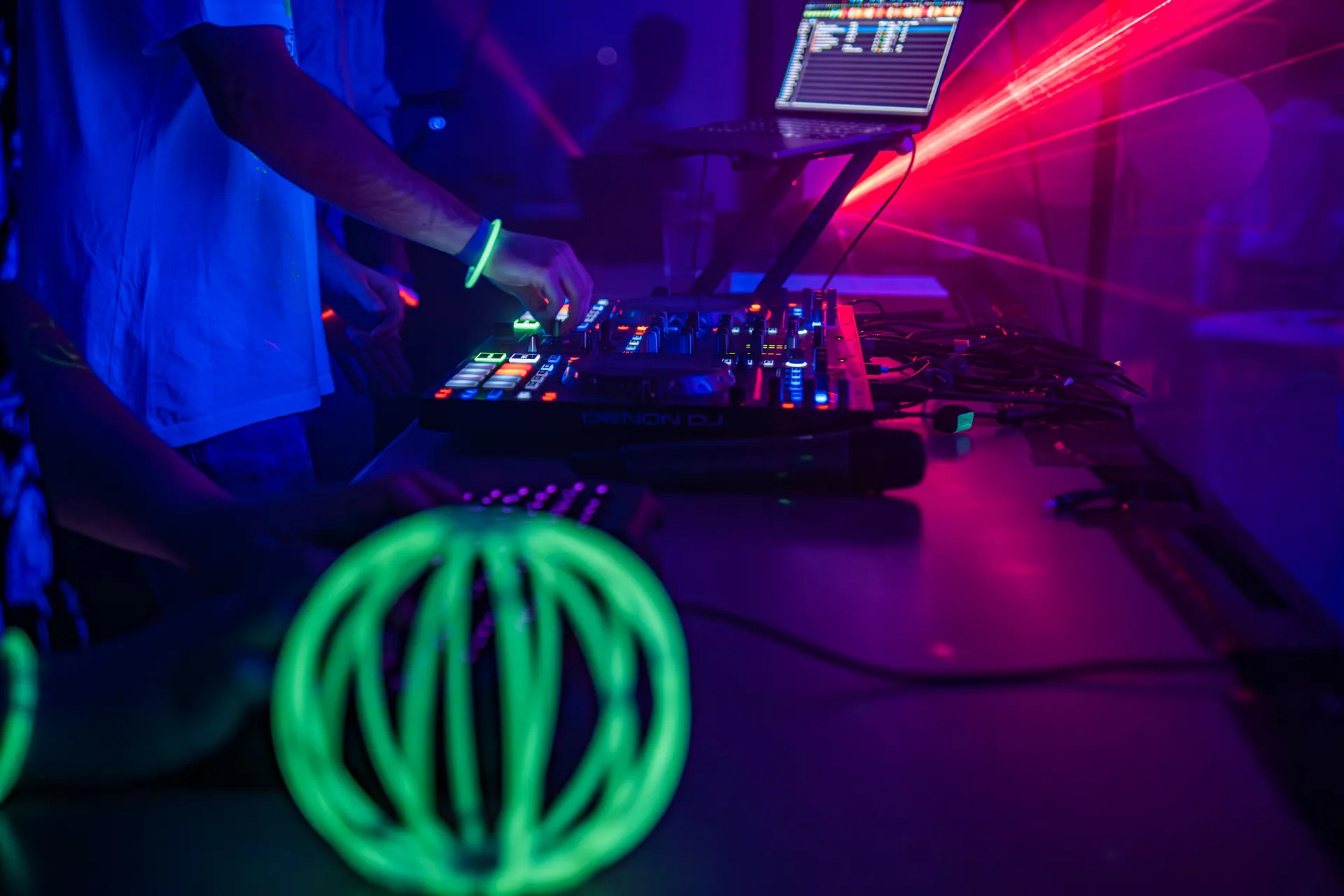 DJ mixing music at a nightclub with vibrant neon lights and professional sound equipment.