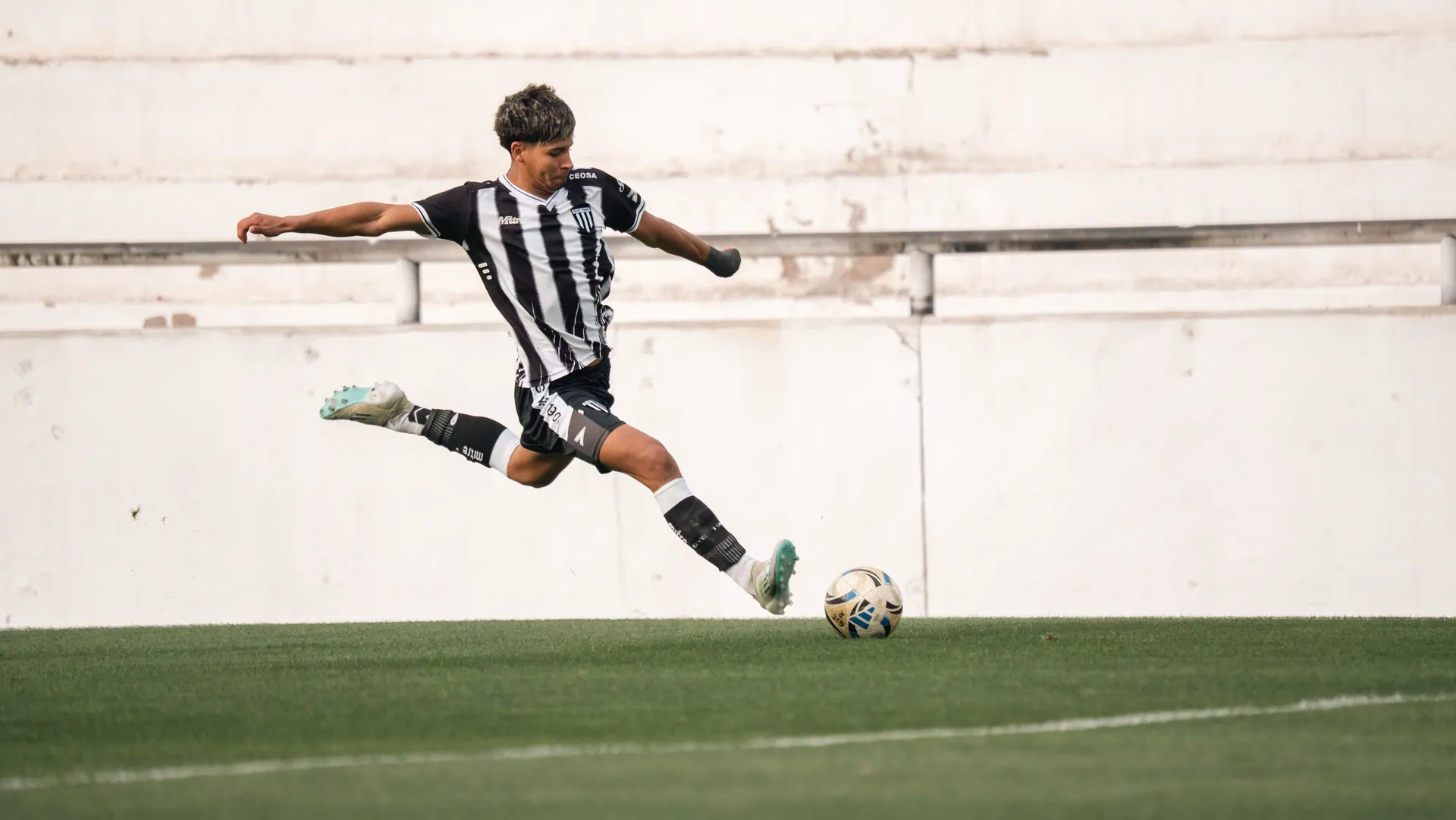 Dynamic shot of a soccer player in mid-air kick on green field.