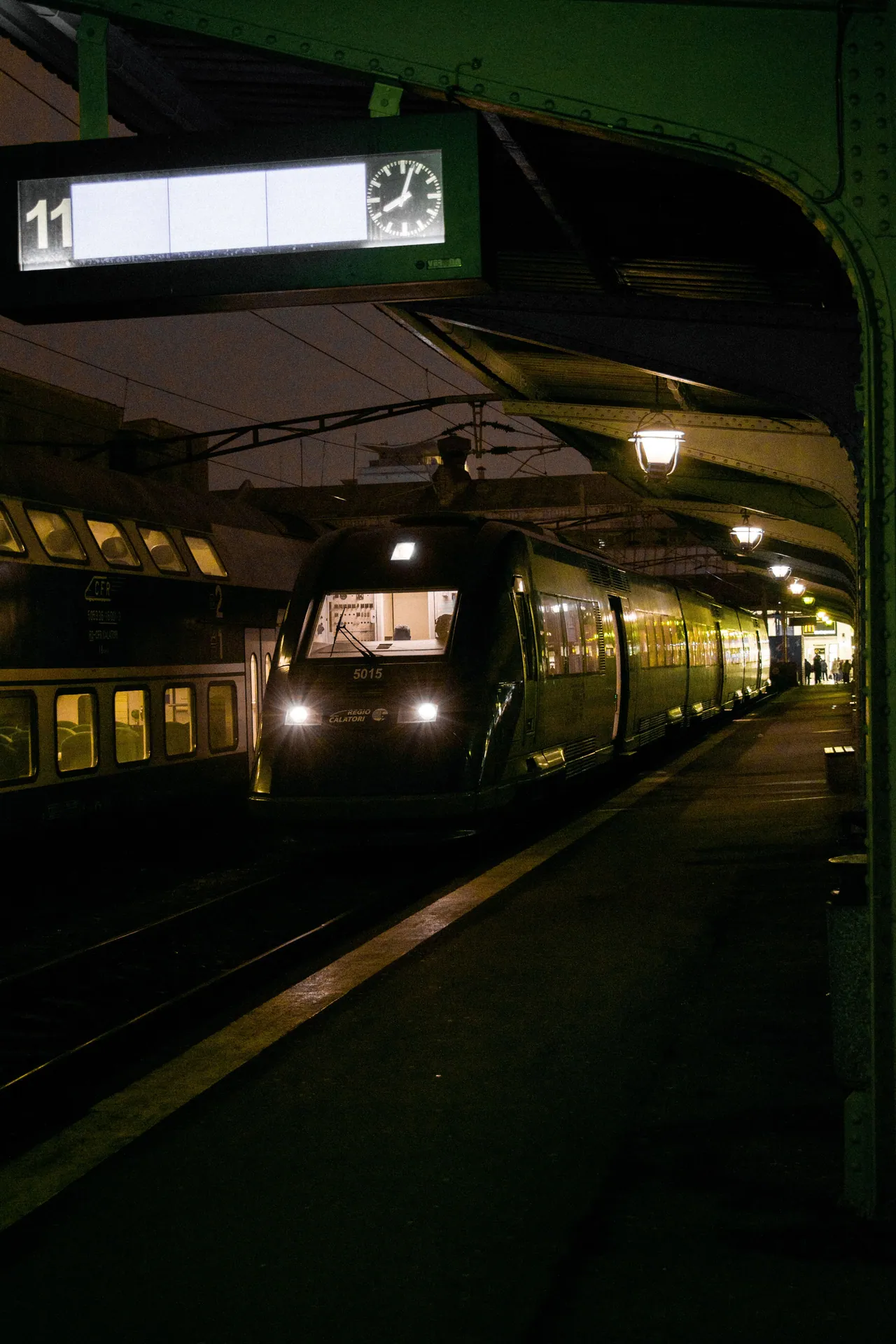 A train stands at a dimly lit railway station platform at night, showcasing urban transportation.