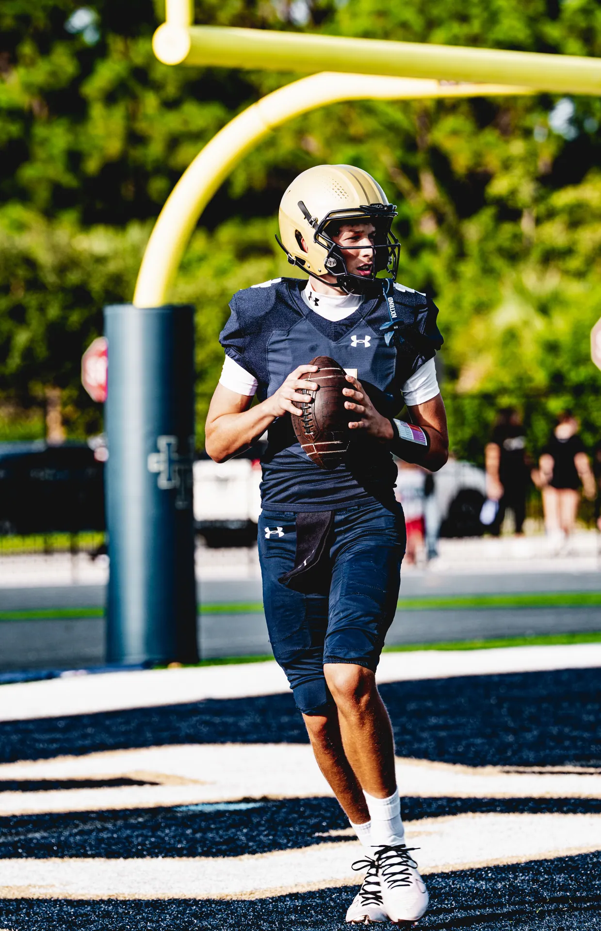 Teenage football player in action on the field, preparing to make a throw.