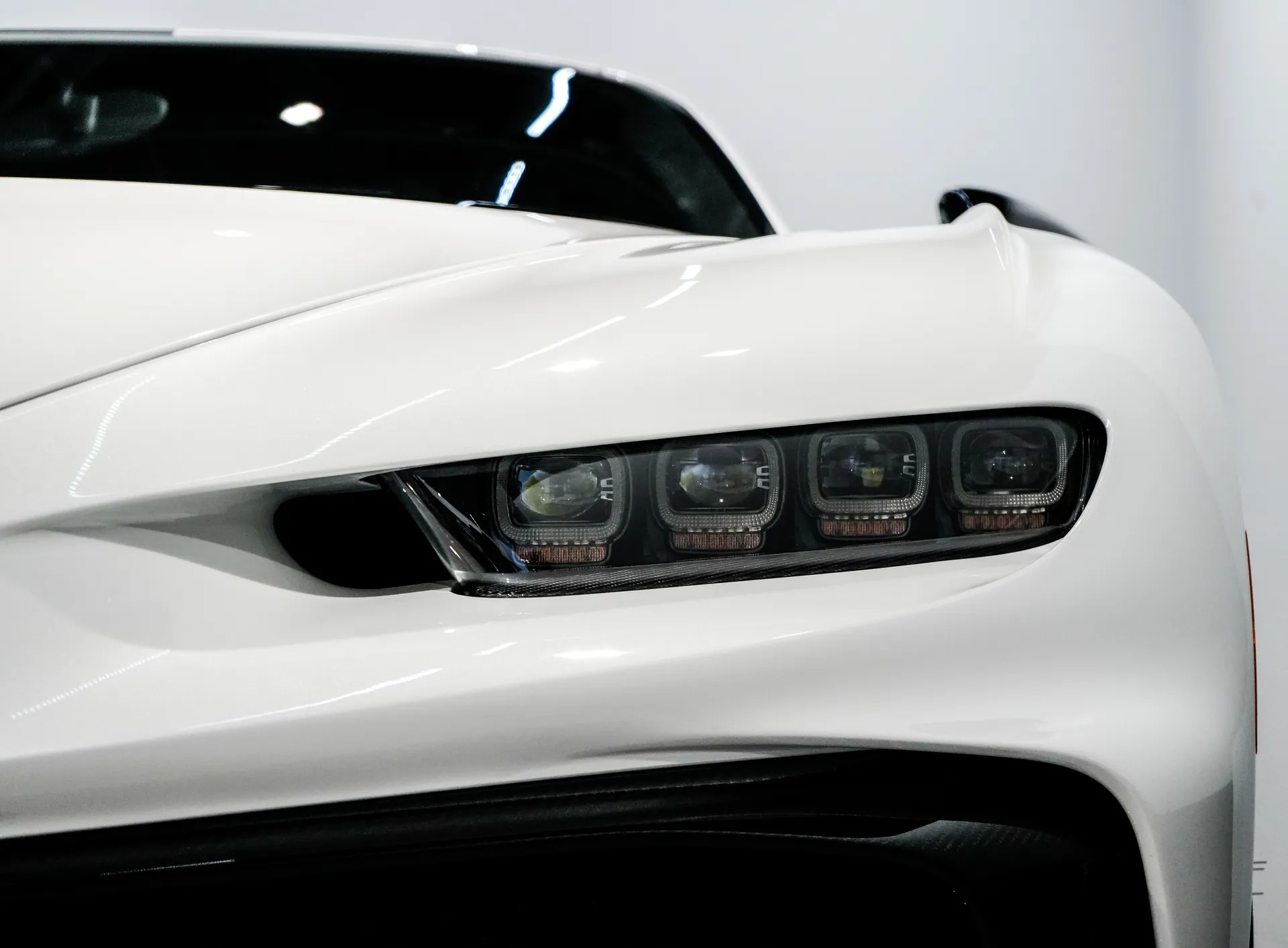 Detailed view of a sleek white sports car headlight showcasing its modern design.