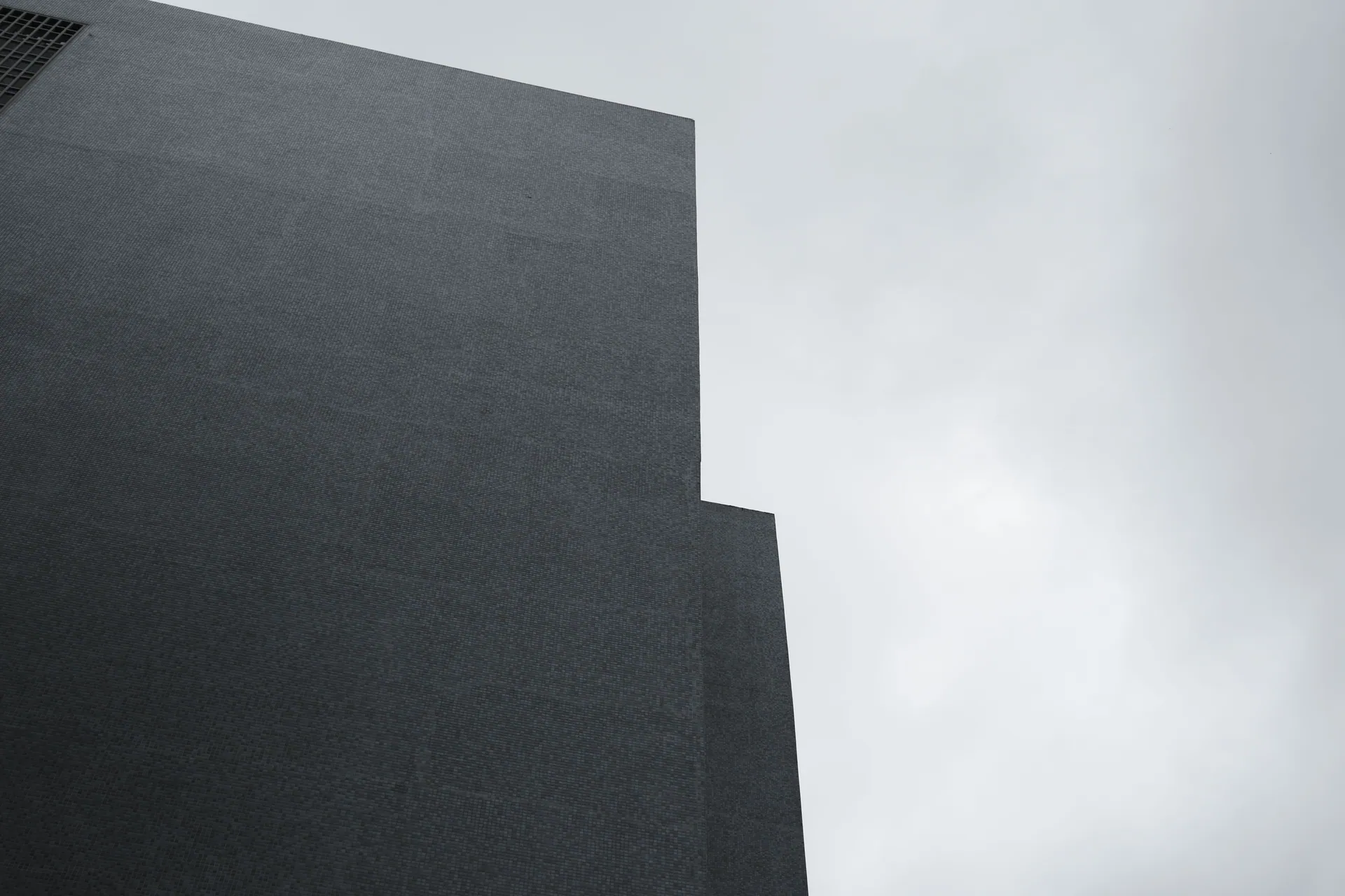 A striking minimalist facade in Istanbul contrasts against a cloudy sky.