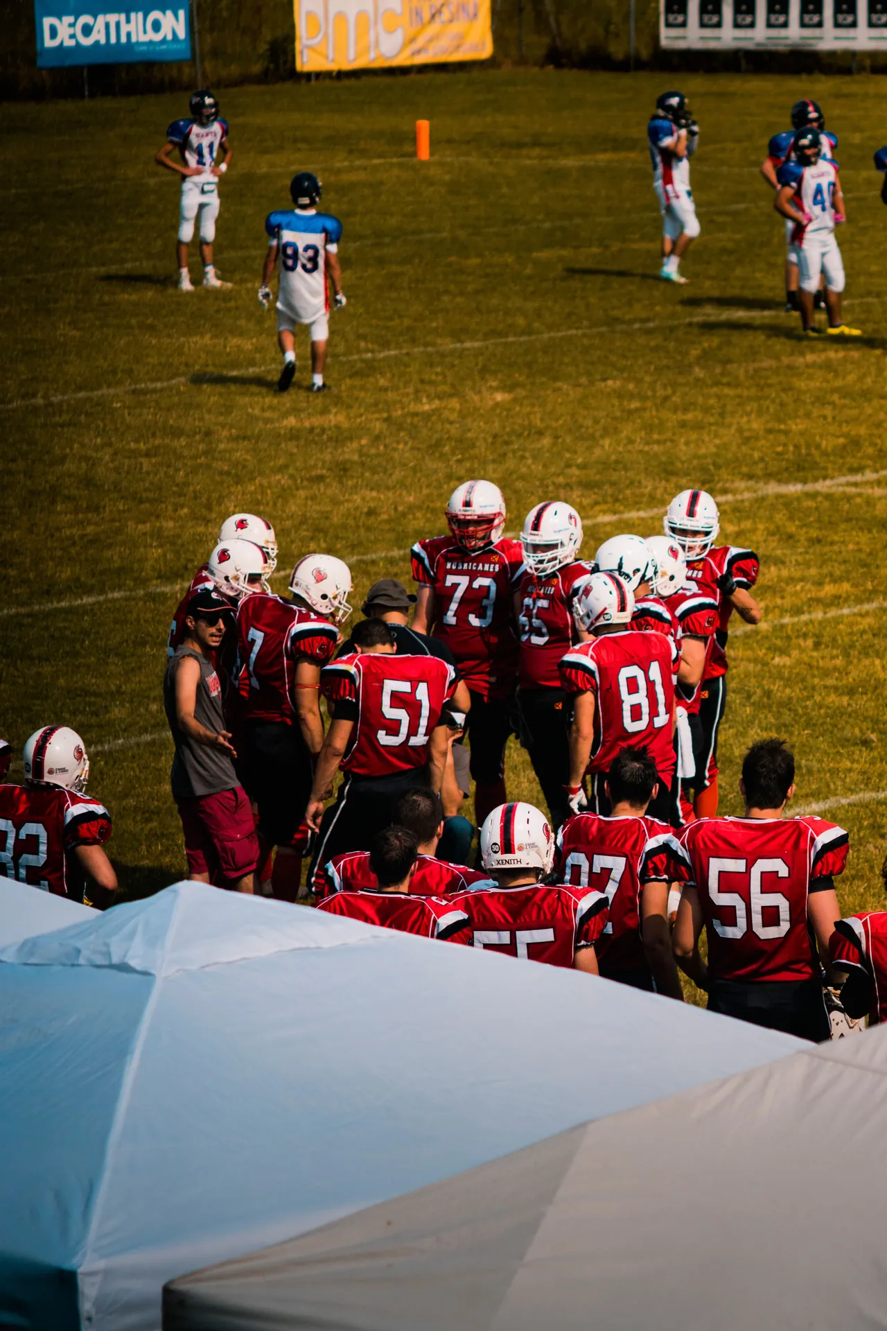 Group of American football players strategizing on a sunny day at a sports field.
