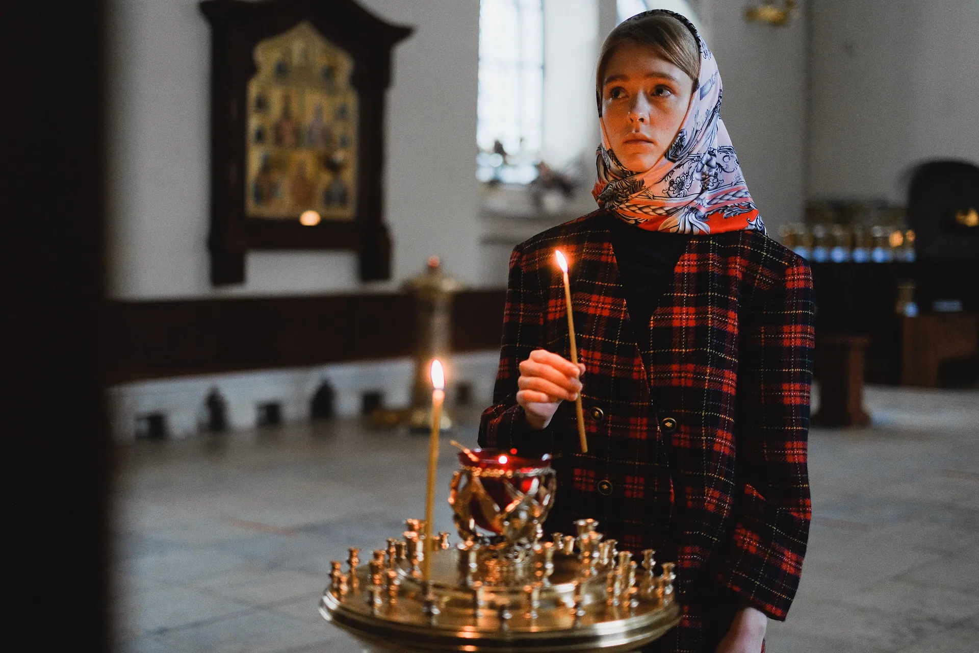 Teenager holding a candle in an Orthodox church, exemplifying spirituality and introspection.