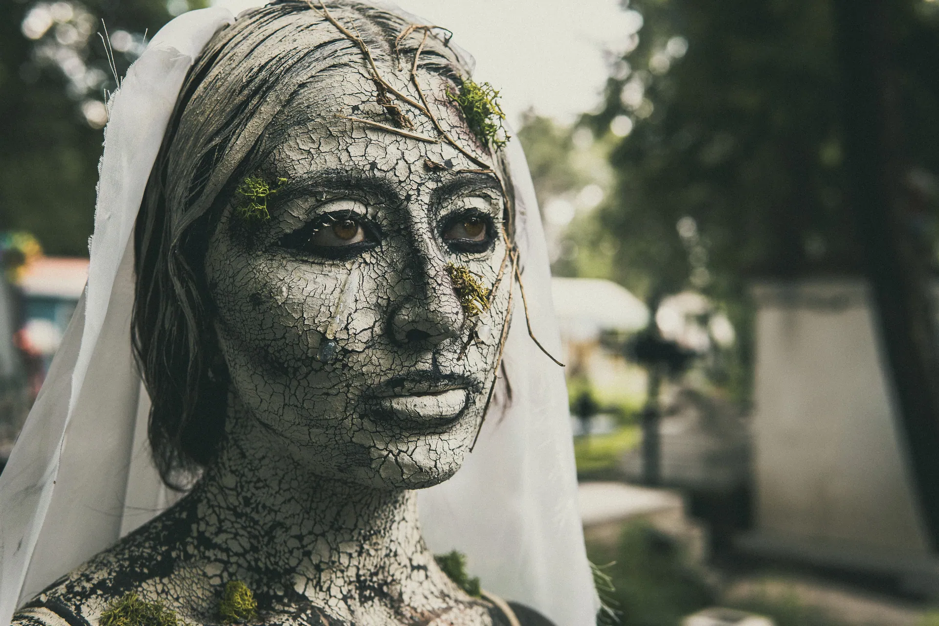 Artistic makeup resembling cracked earth in cemetery scene captures haunting beauty.