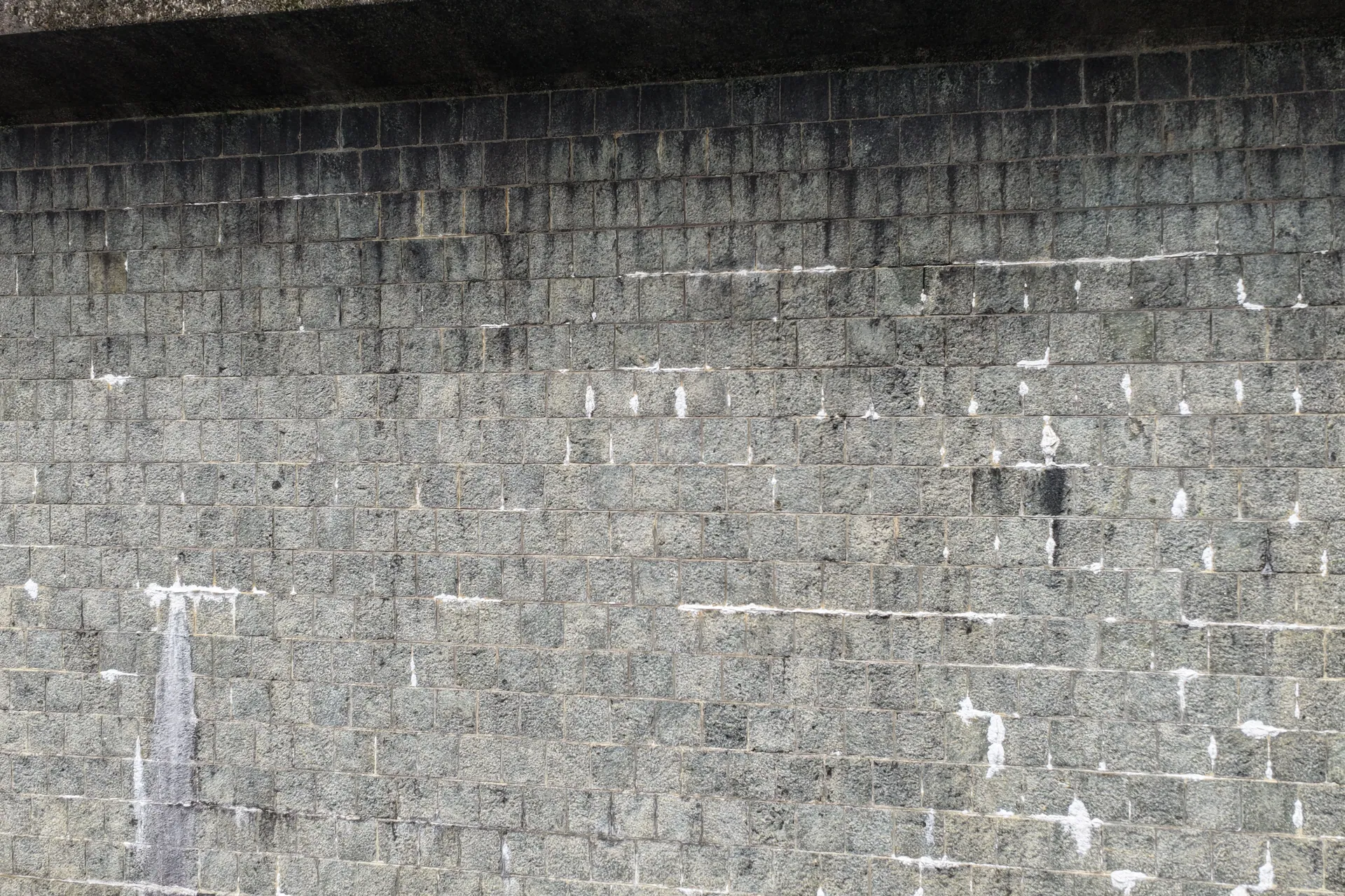 Close-up of a worn gray stone wall exterior with visible texture and weather wear.