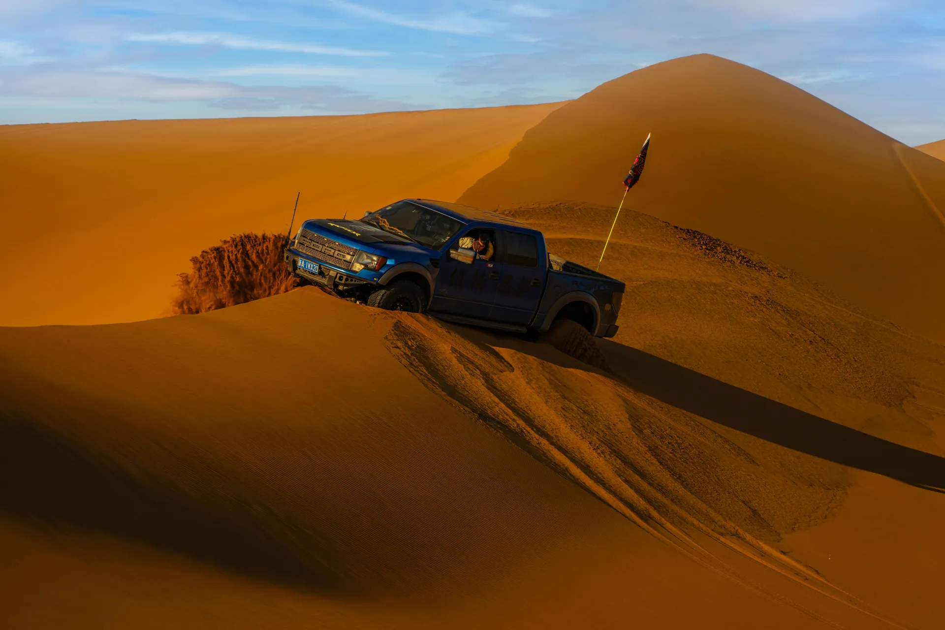 A pickup truck navigates desert dunes, showcasing thrilling off-road adventure amidst a sandy landscape.