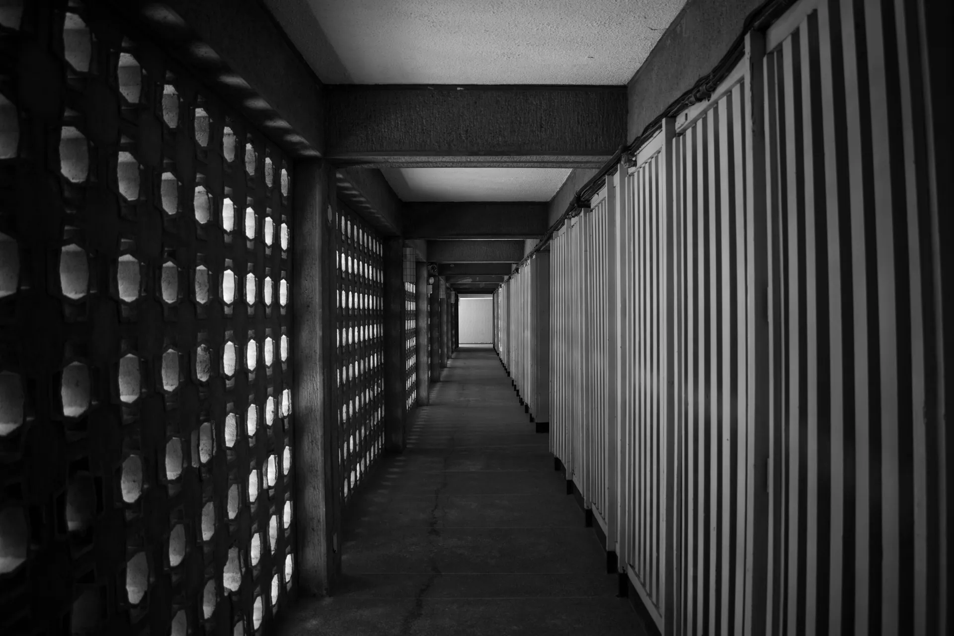 A dramatic black and white view of a geometric architectural corridor with striped walls.