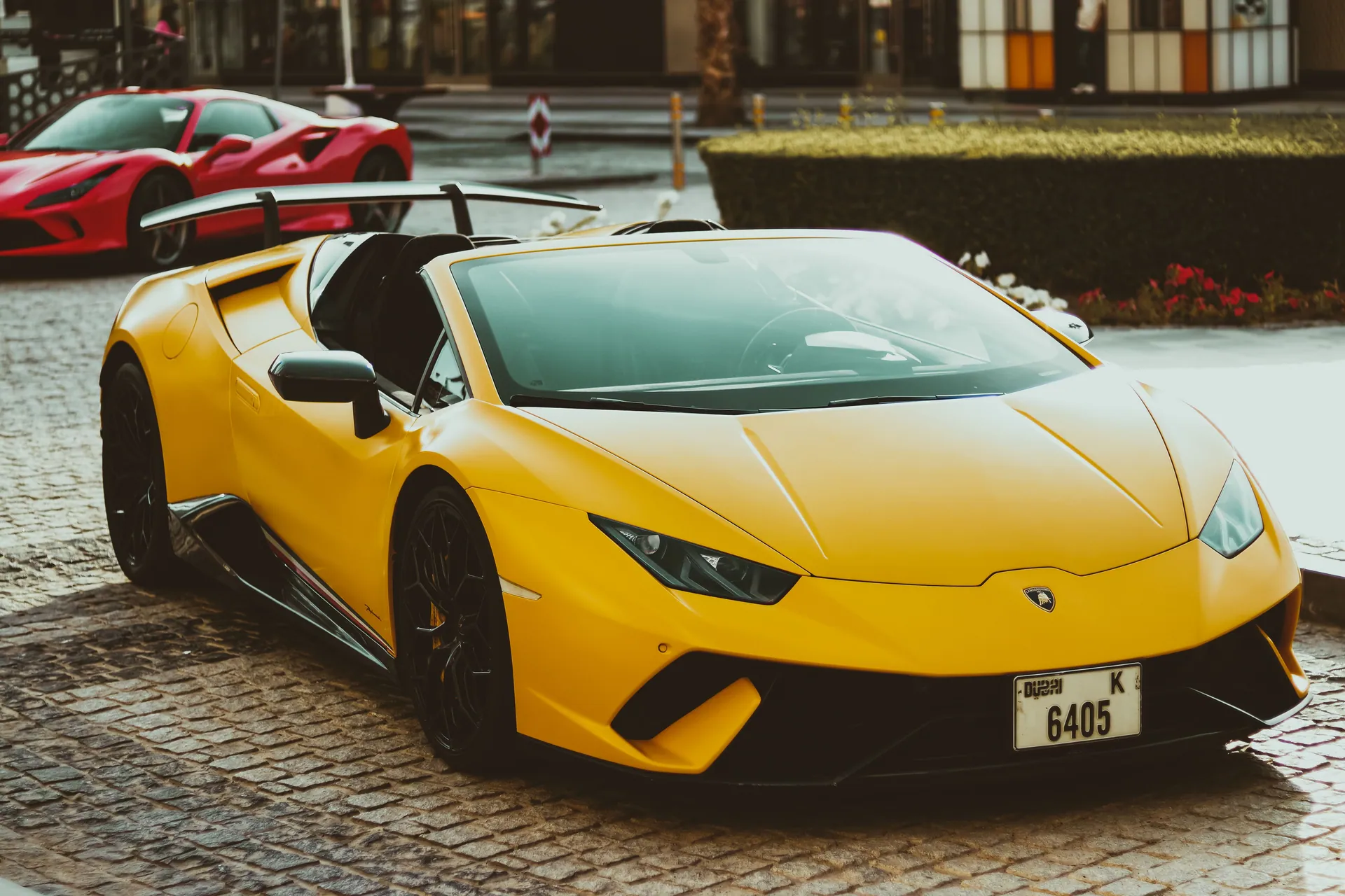 A striking yellow Lamborghini parked on a cobblestone street in Dubai, exuding luxury and style.