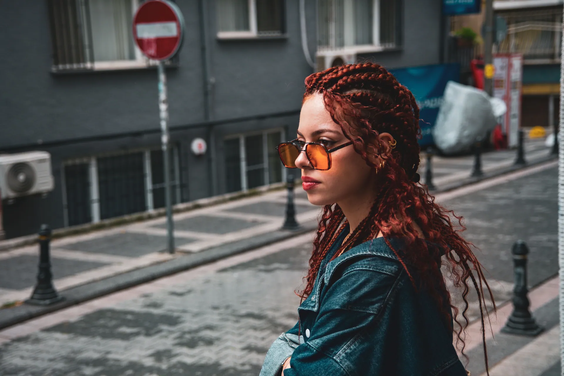 Stylish woman with red hair and sunglasses in an urban setting.
