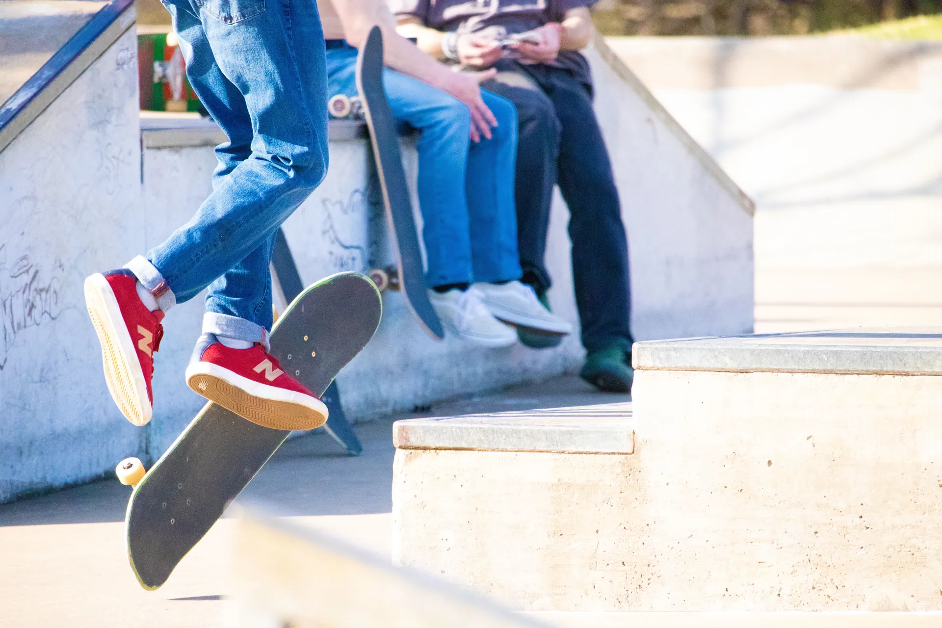 Exciting skateboarding action captured during a kick flip trick at a local skate park, featuring trendy red sneakers.