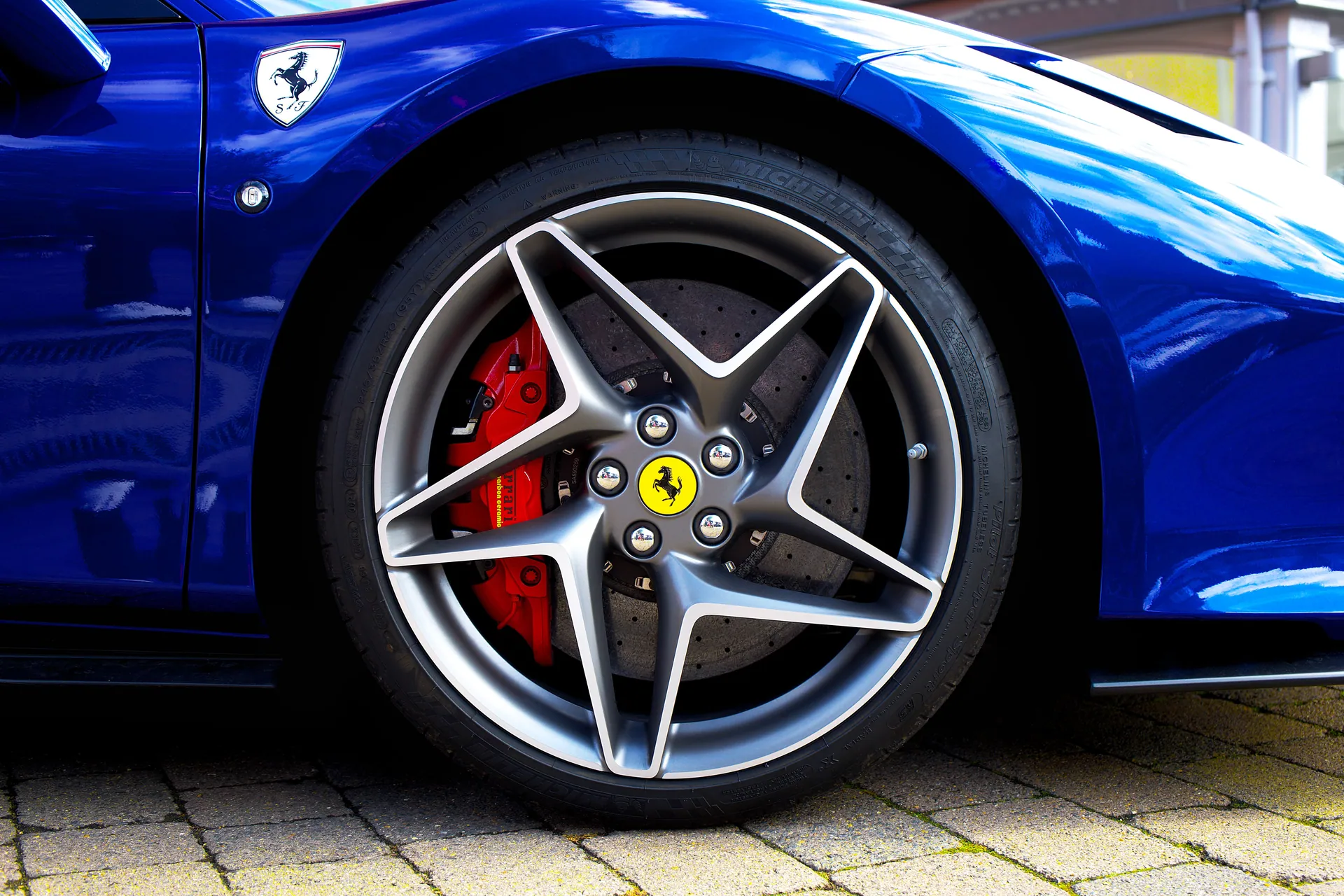 Detailed shot of a blue sports car wheel and emblem in the UK.