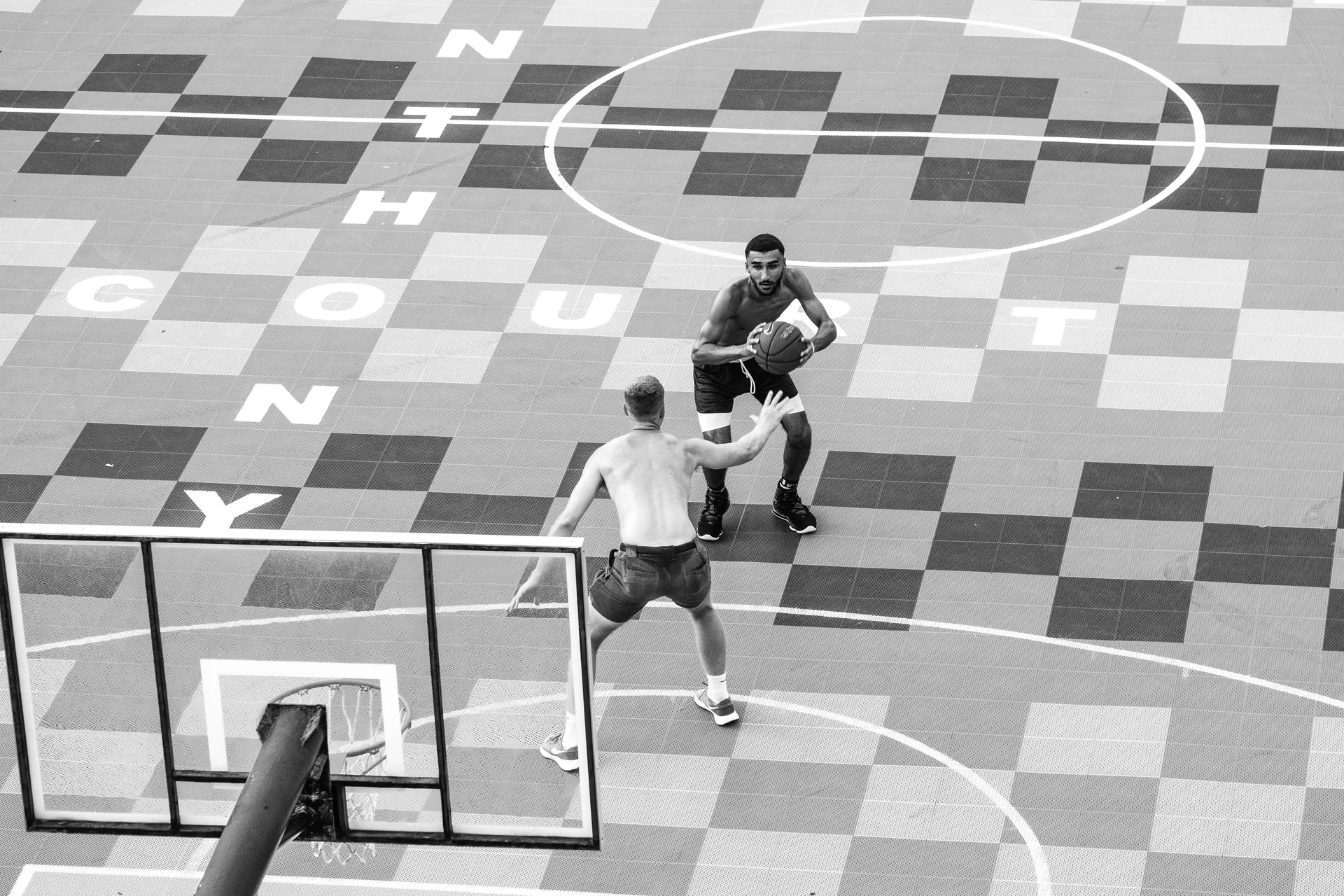 High angle view of shirtless men playing basketball on a unique urban court.