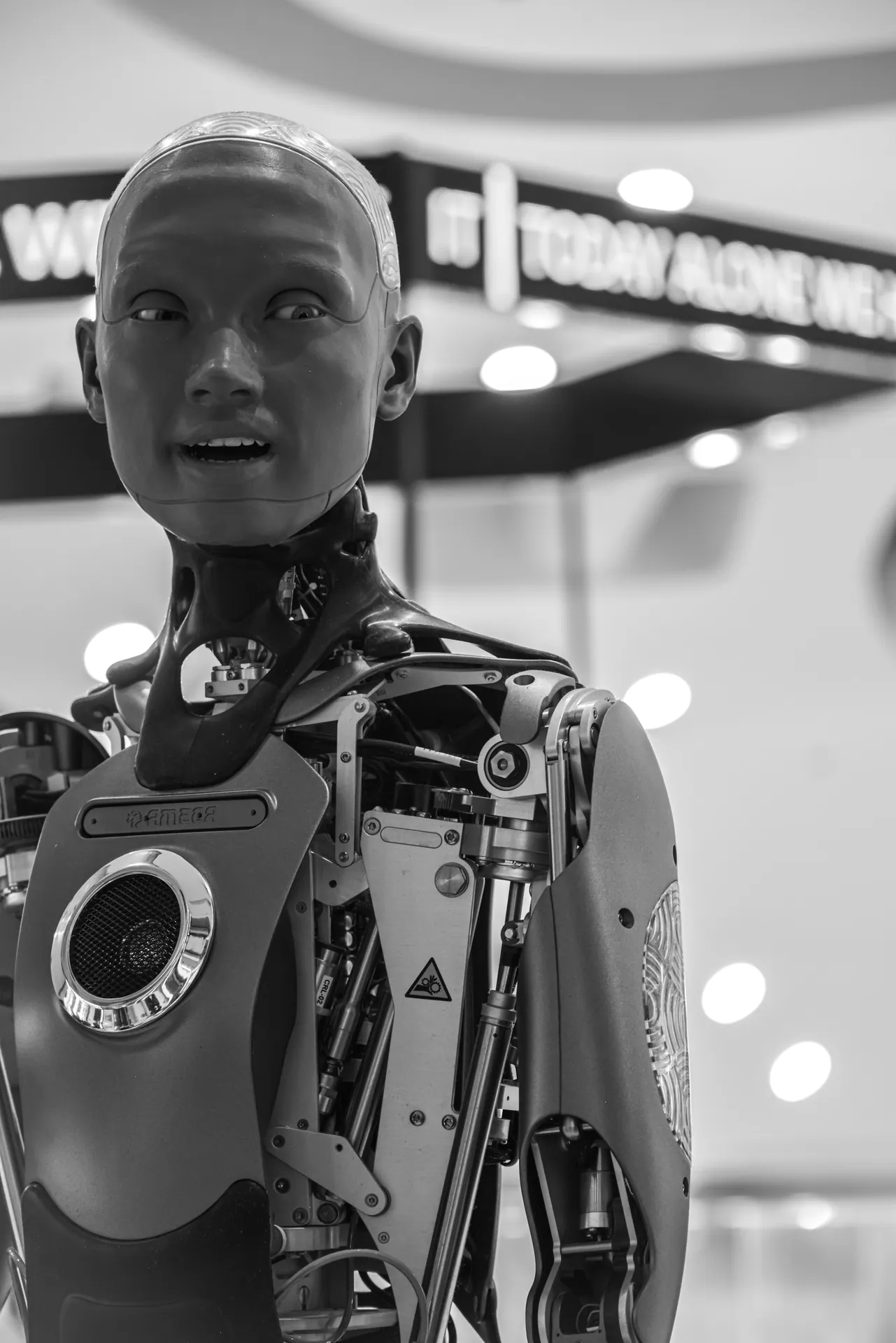 Detailed black and white image of an advanced humanoid robot with visible mechanical parts, set indoors.