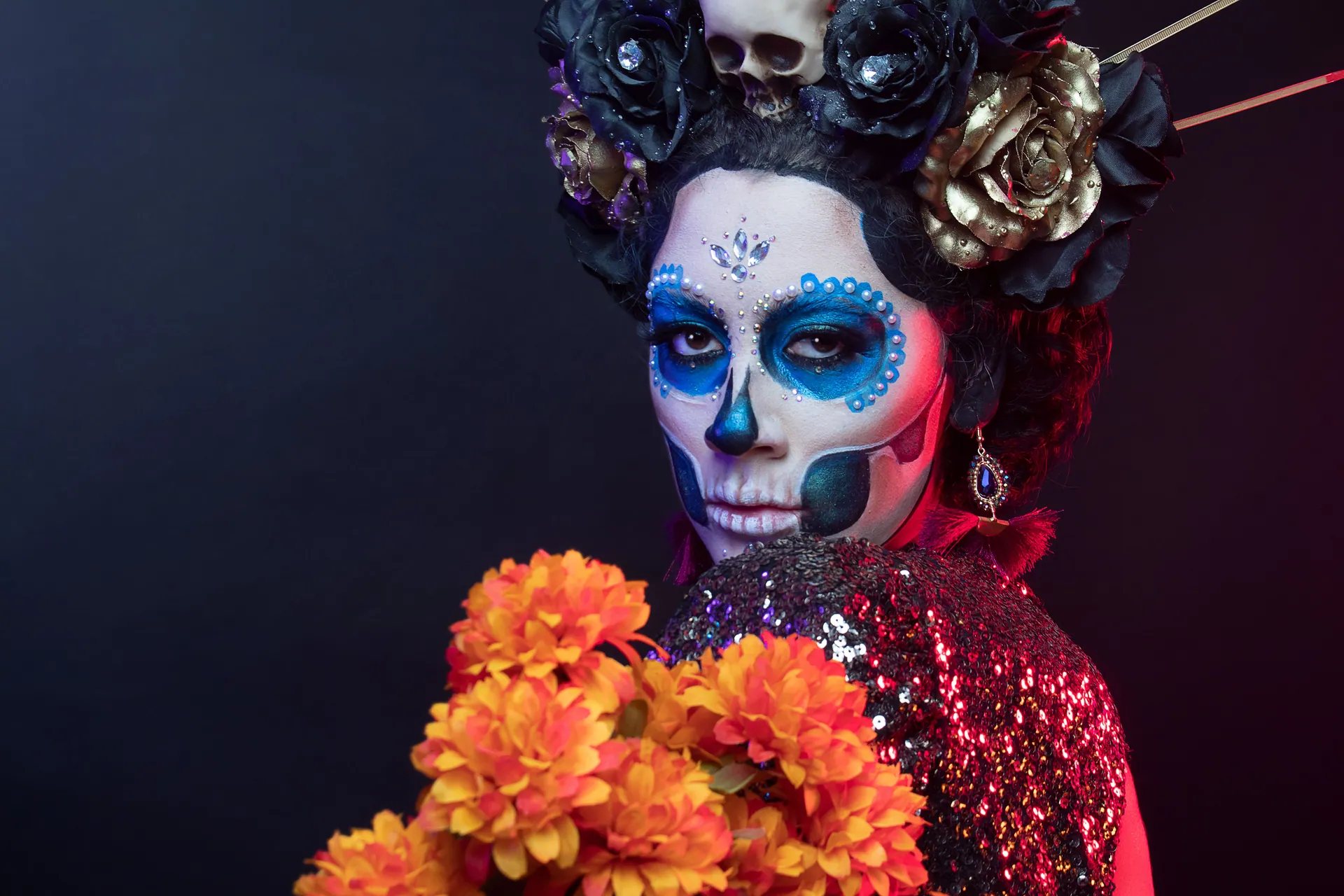 Vibrant portrait of a woman with Day of the Dead makeup and floral adornments.