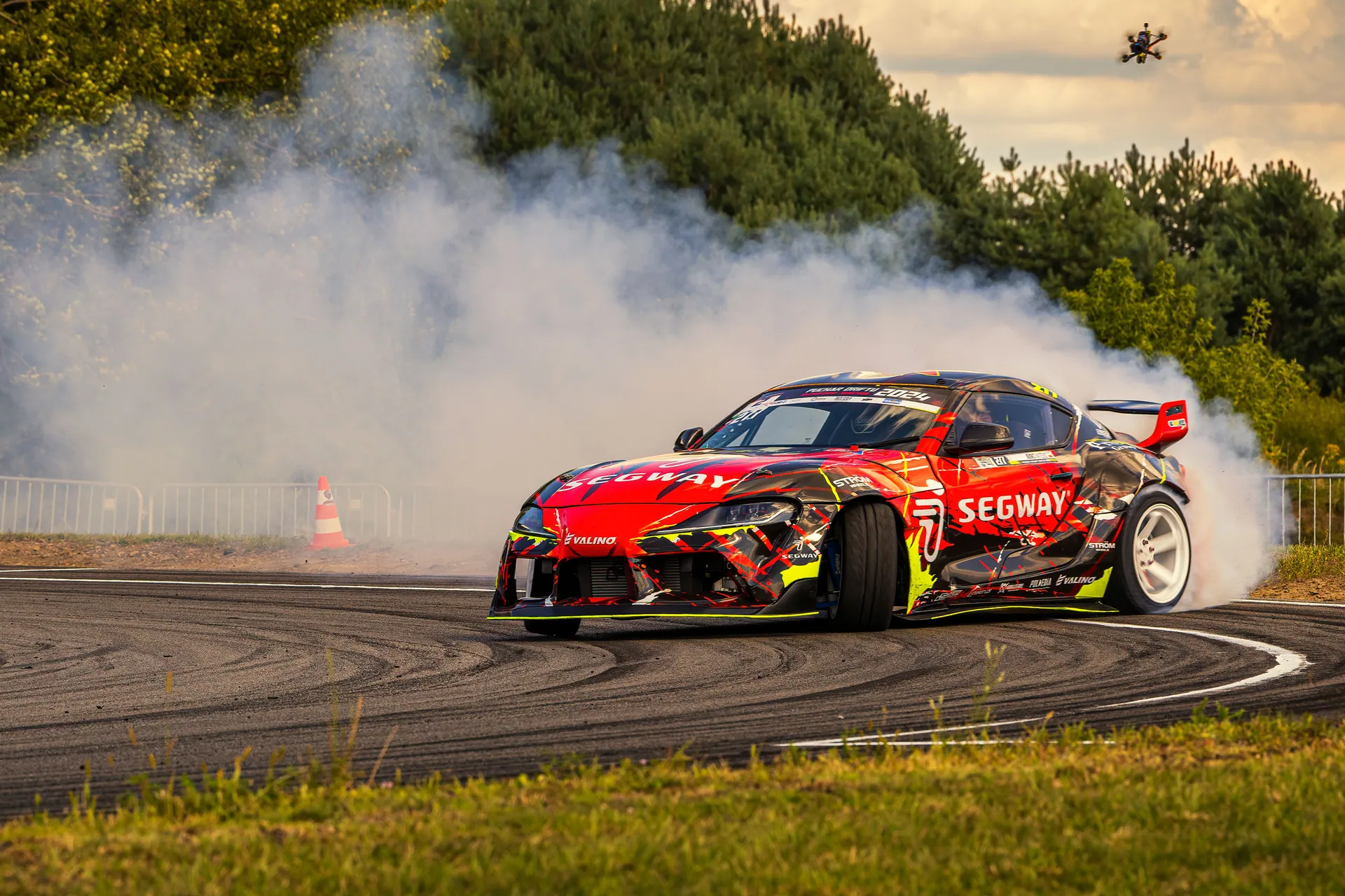 A dynamic car drifts with smoke on a race track surrounded by nature, capturing speed and power.