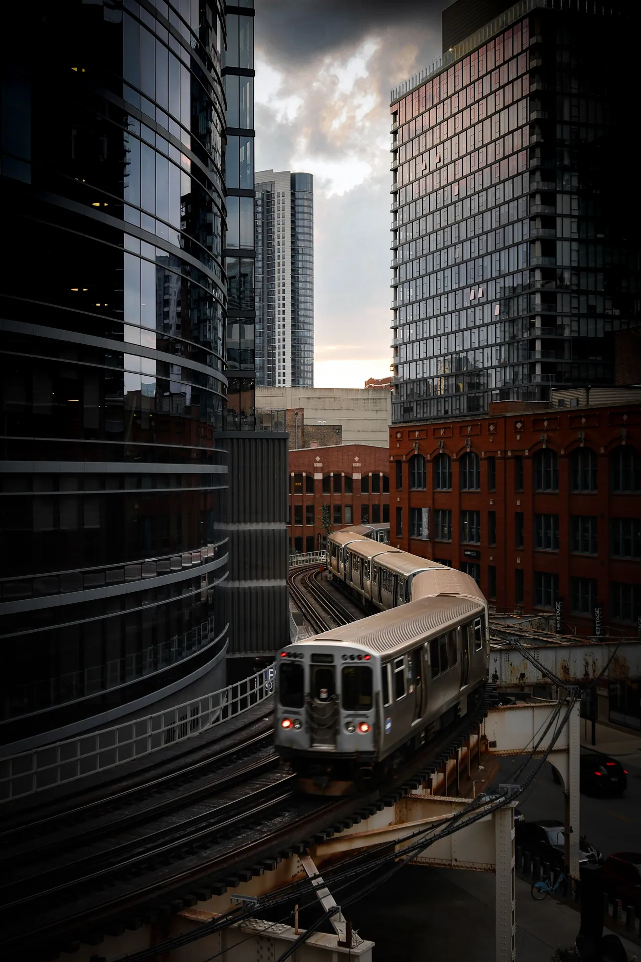 A city train navigates through modern skyscrapers and classic architecture at dusk.