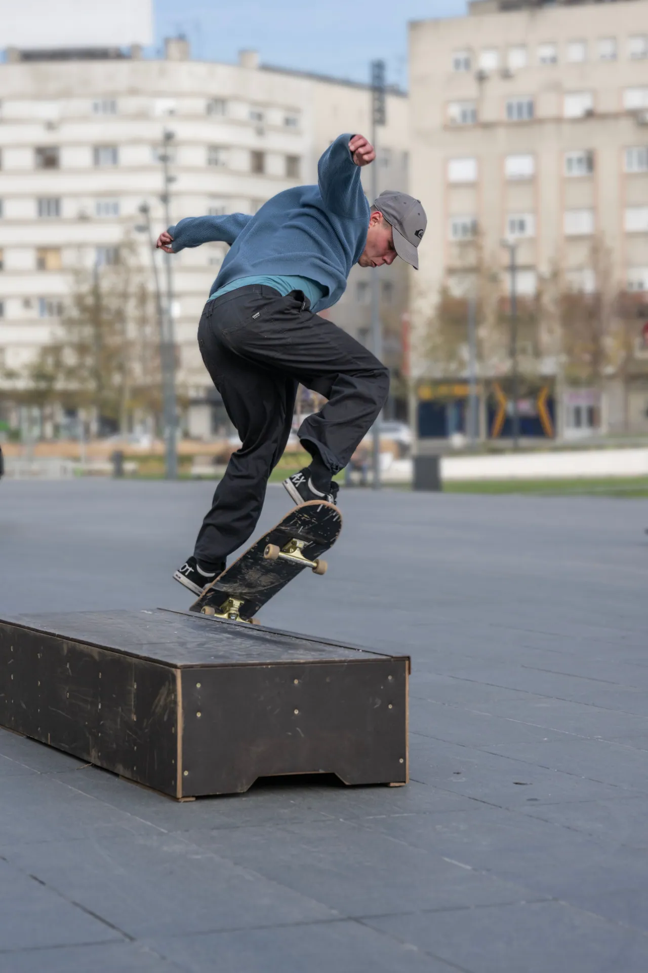 Skateboarder executing a trick on a ledge in a city park setting.
