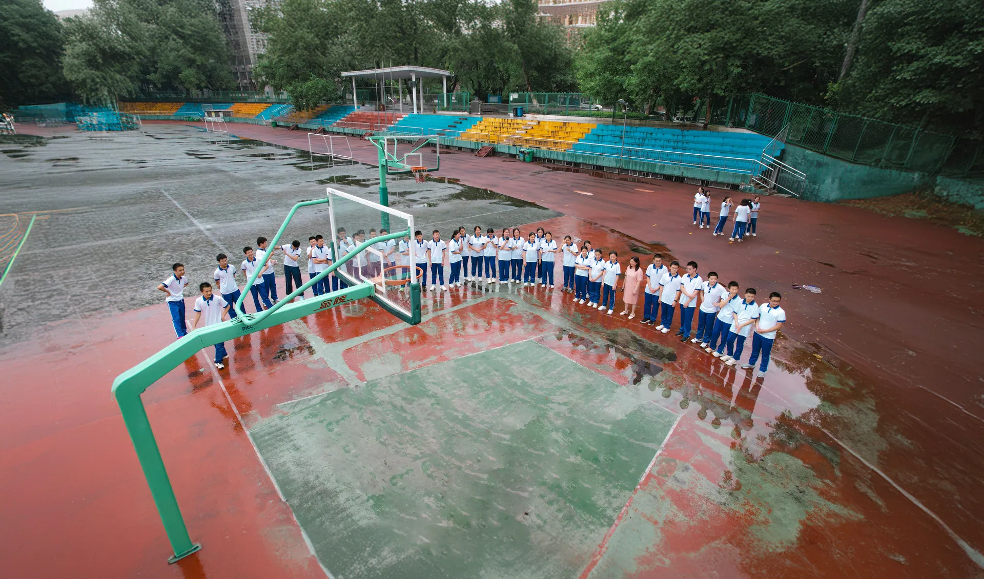 Students gather on a colorful outdoor basketball court, post-rain, in Jiangxi, China.
