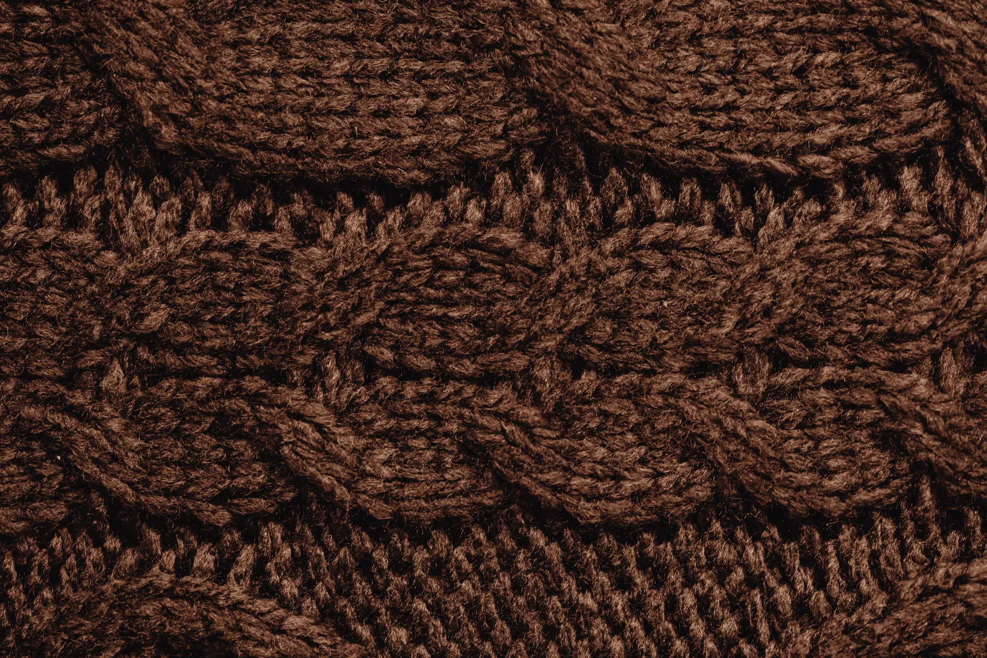 Detailed close-up of a brown knitted fabric, showcasing intricate texture and pattern.