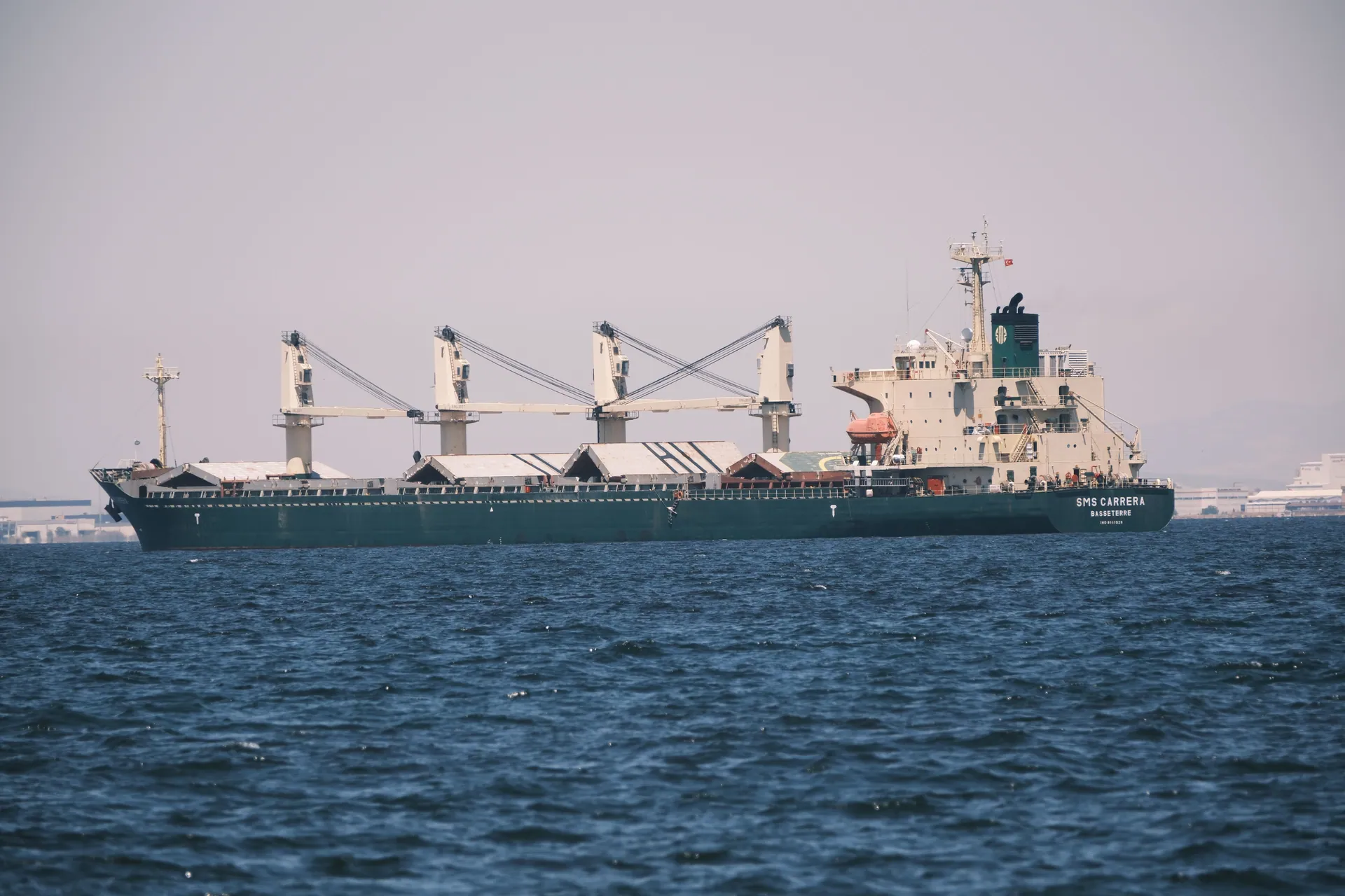 A cargo ship navigates the calm waters off the coast of İzmir, Türkiye.