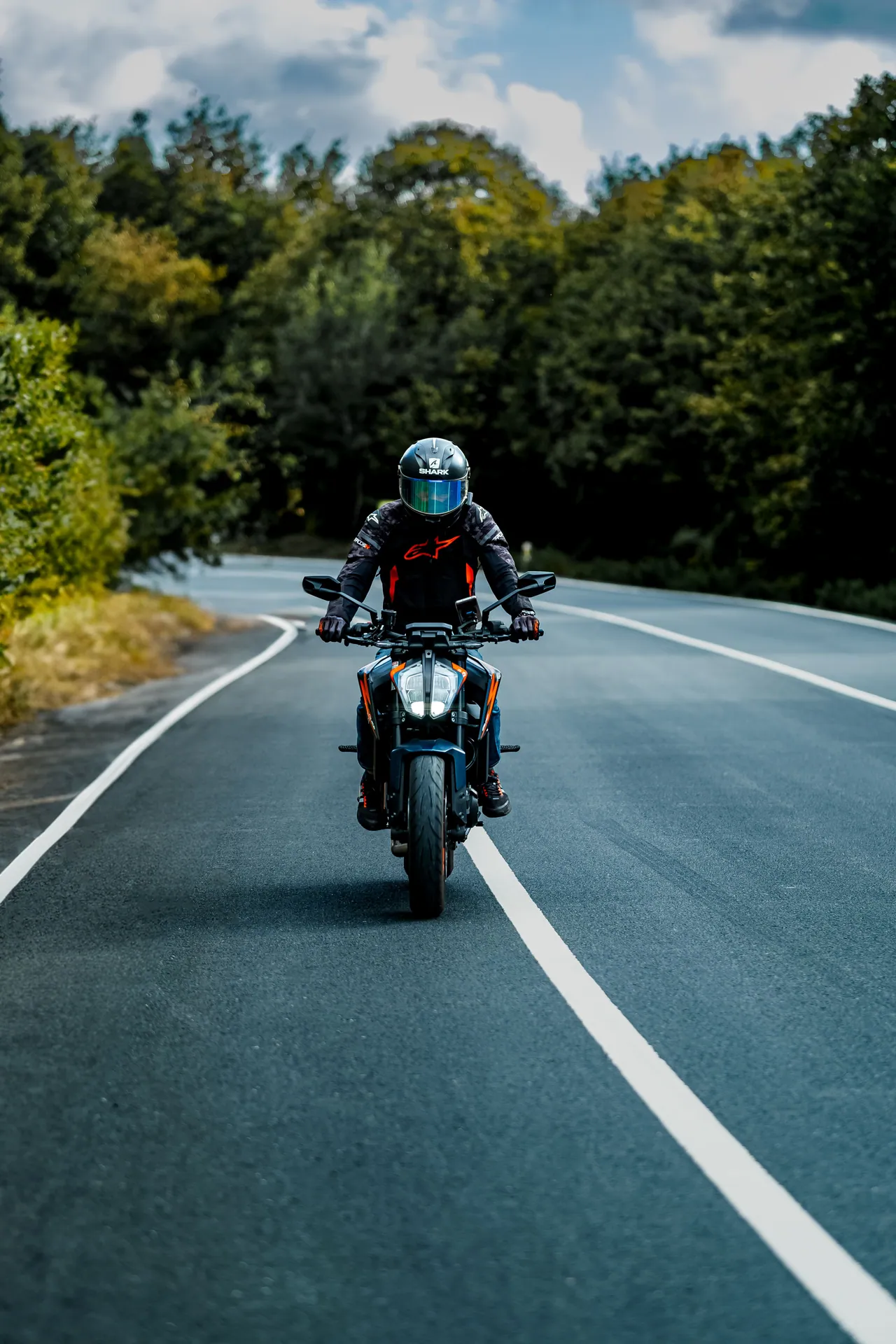 Motorcyclist rides through a forest road under a clear sky, capturing the essence of freedom and adventure.