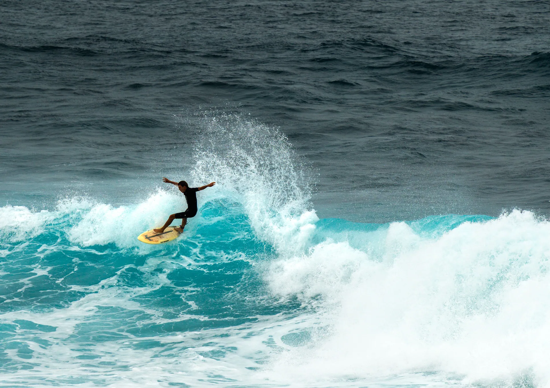 A surfer skillfully rides a powerful wave, showcasing athleticism and balance in an ocean setting.