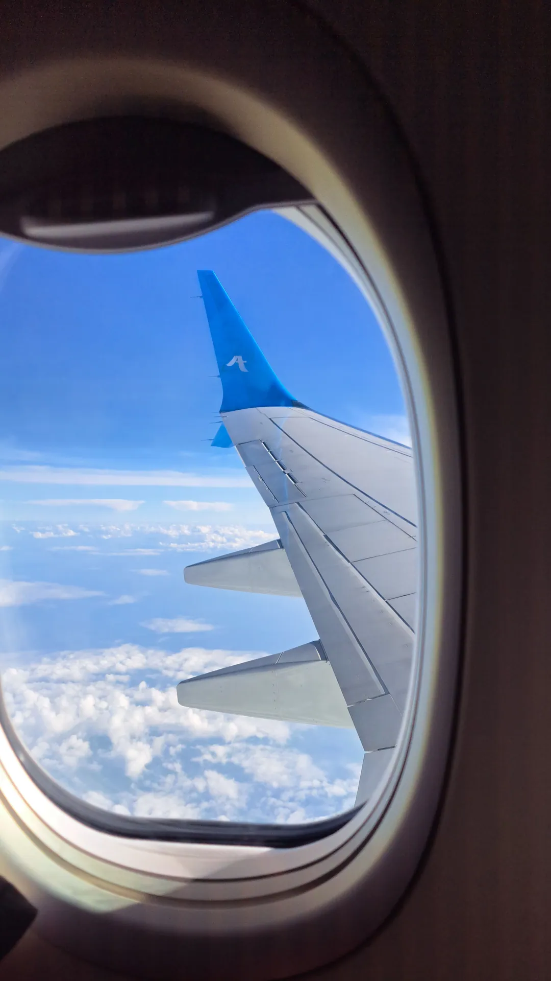Stunning view of airplane wing against a backdrop of blue sky and clouds.