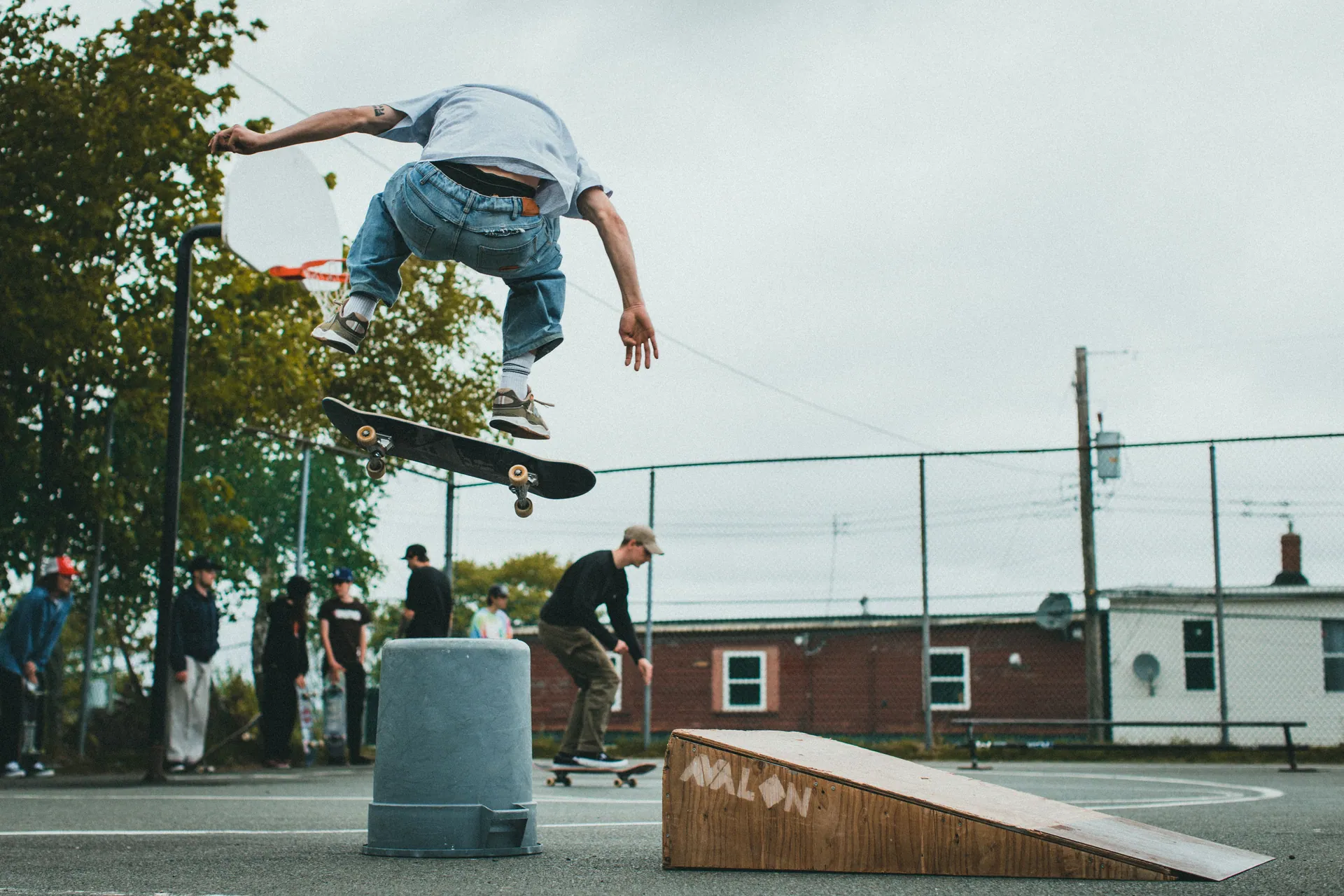 Skateboarder performs a high-flying stunt over a ramp in an urban skatepark setting.