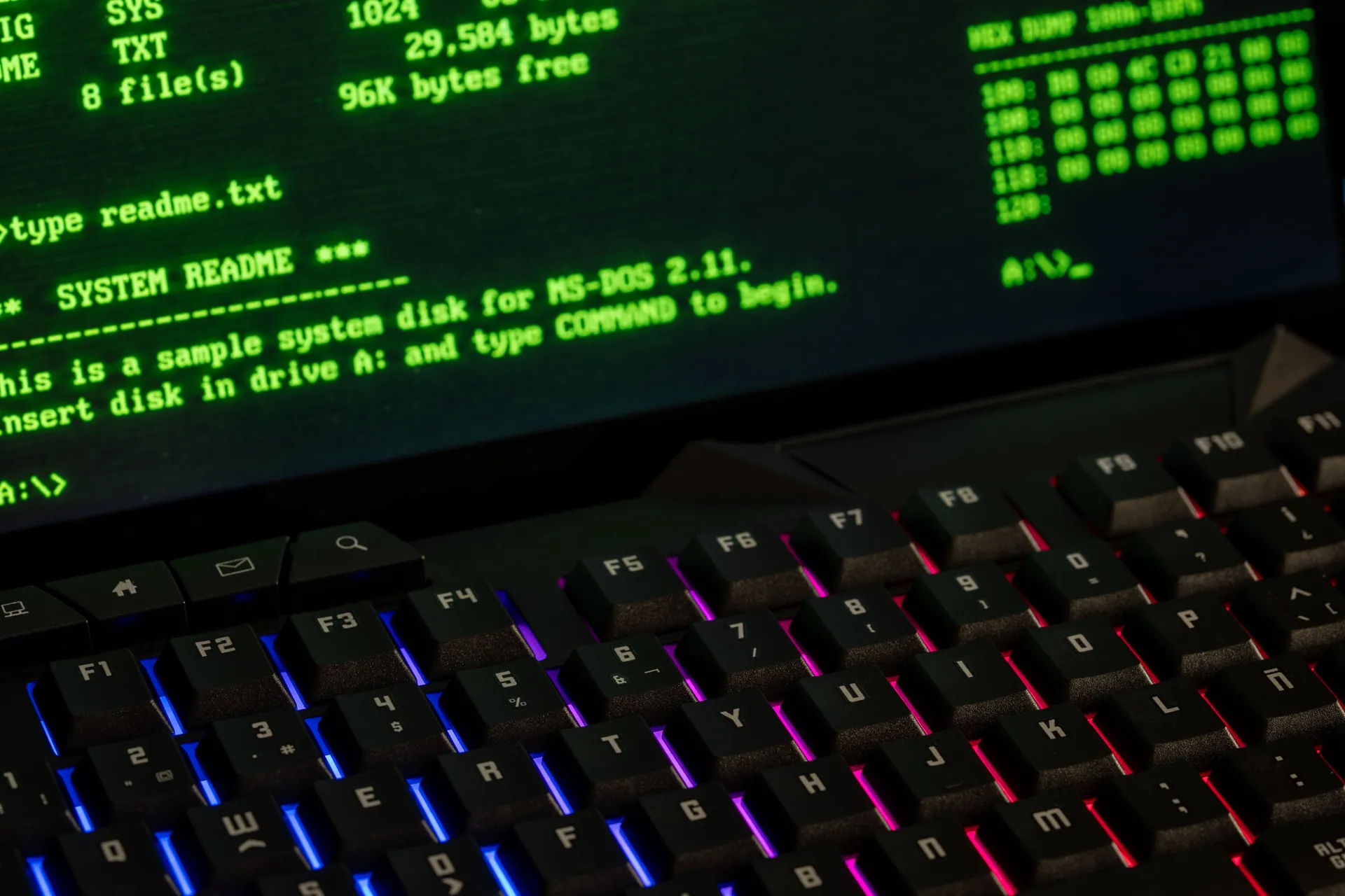 Close-up of a retro computer screen displaying MS-DOS commands with a vibrant keyboard.